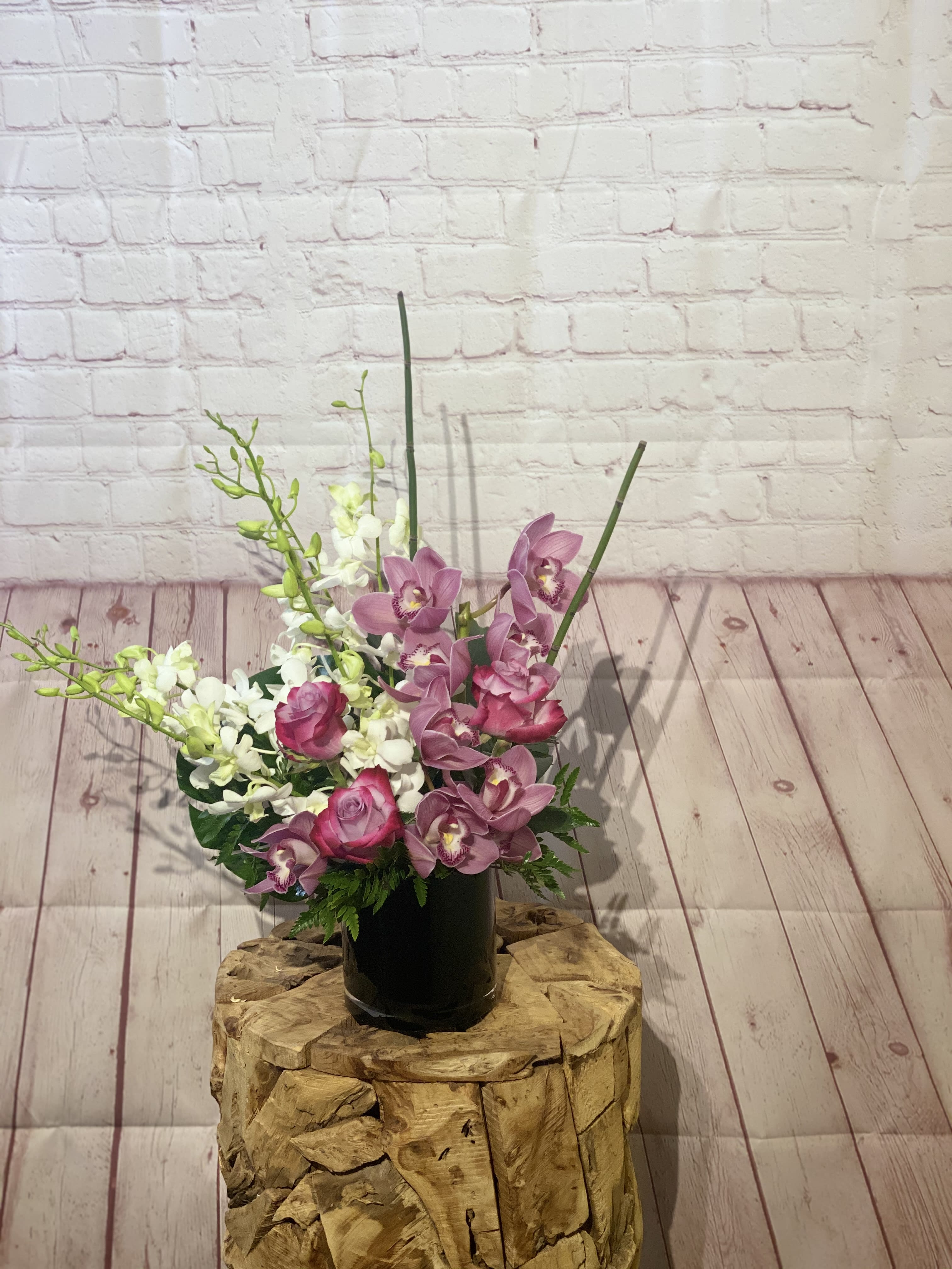 Pink orchids and roses arranged in a black vase