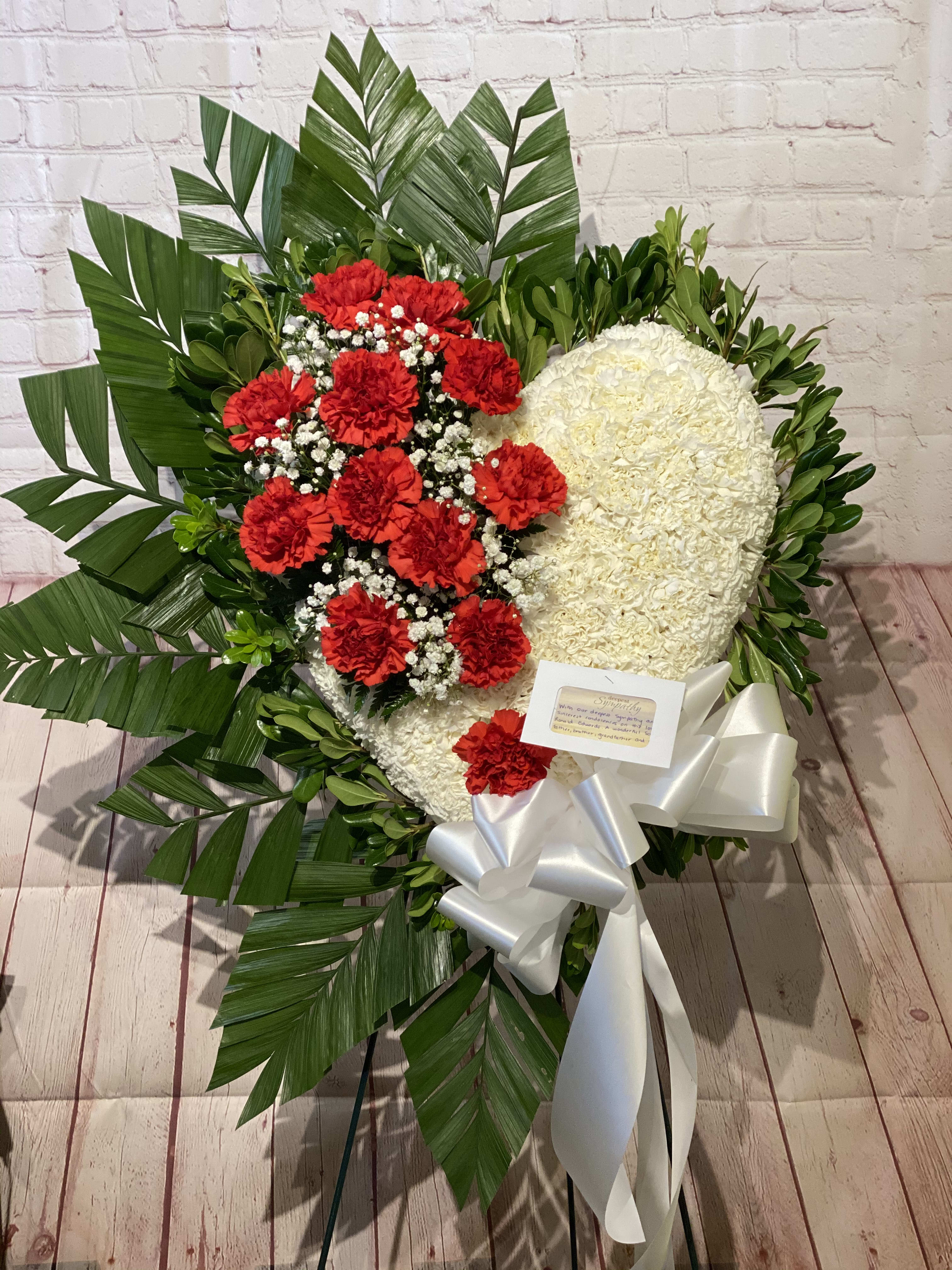 Heart-shaped floral wreath with red and white flowers and a white ribbon