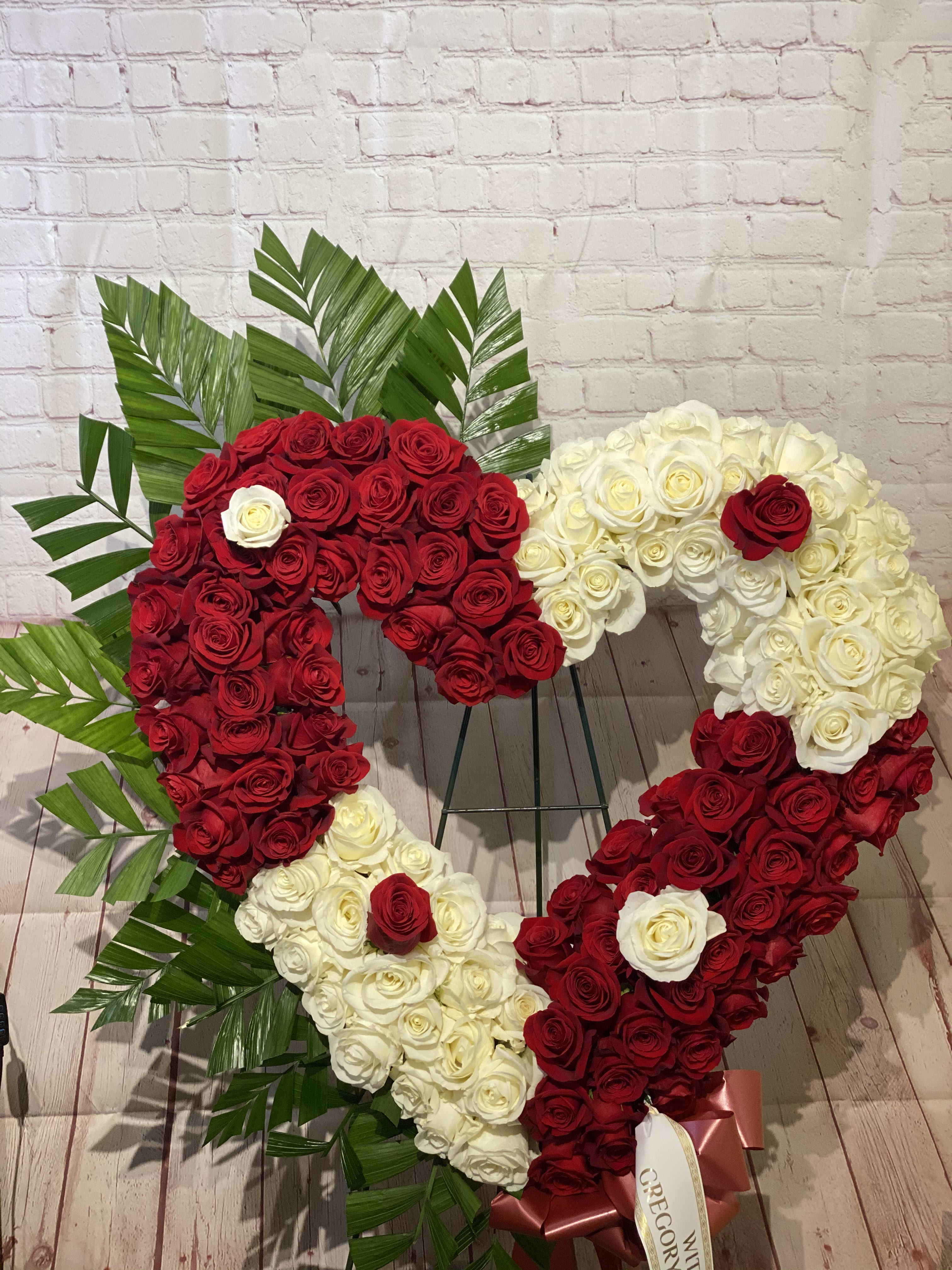 Heart-shaped arrangement of red and white roses with palm leaves