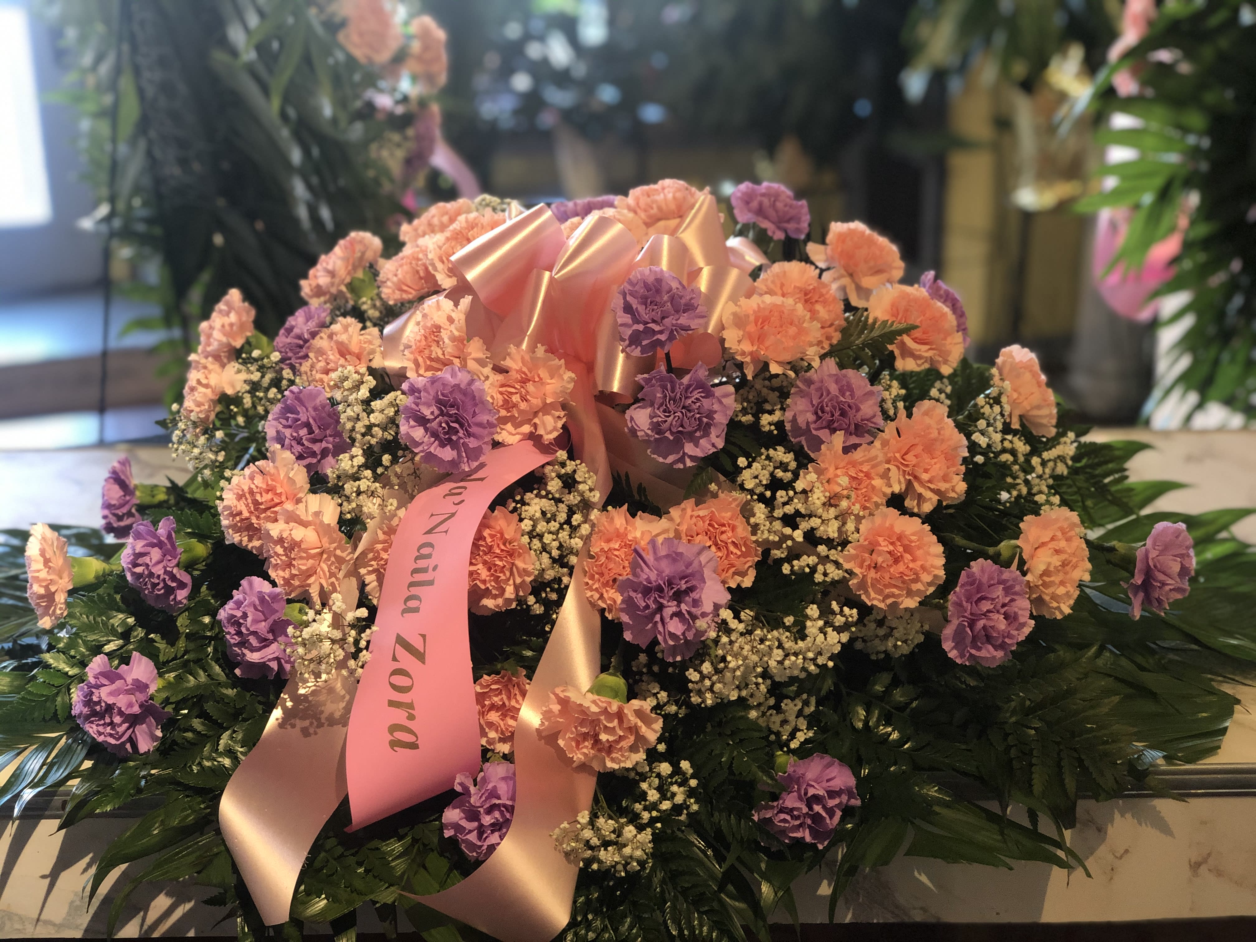 Large floral arrangement of pink and purple carnations with a satin ribbon