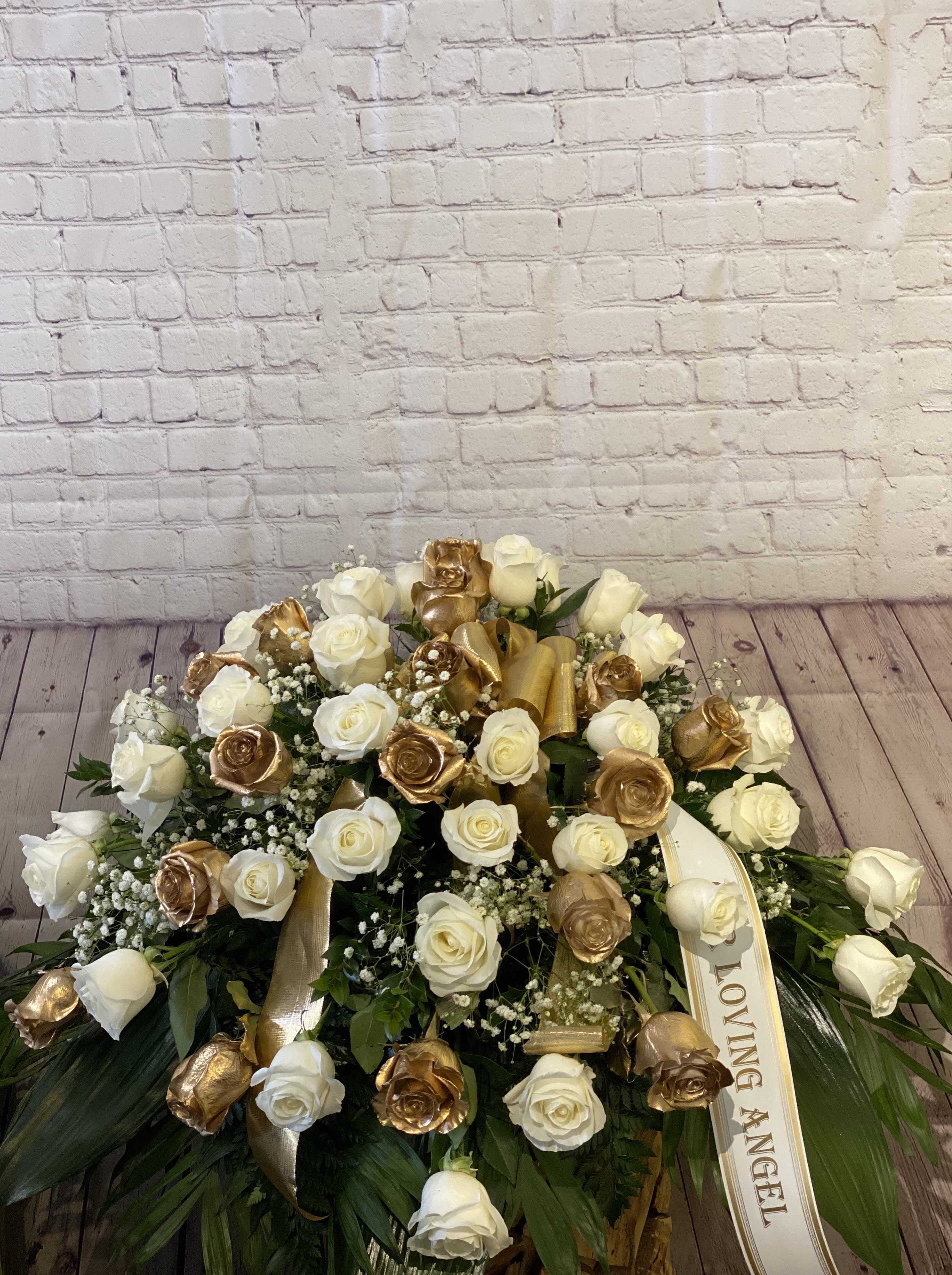 Large white and gold rose arrangement with a ribbon reading "Loving Angel"