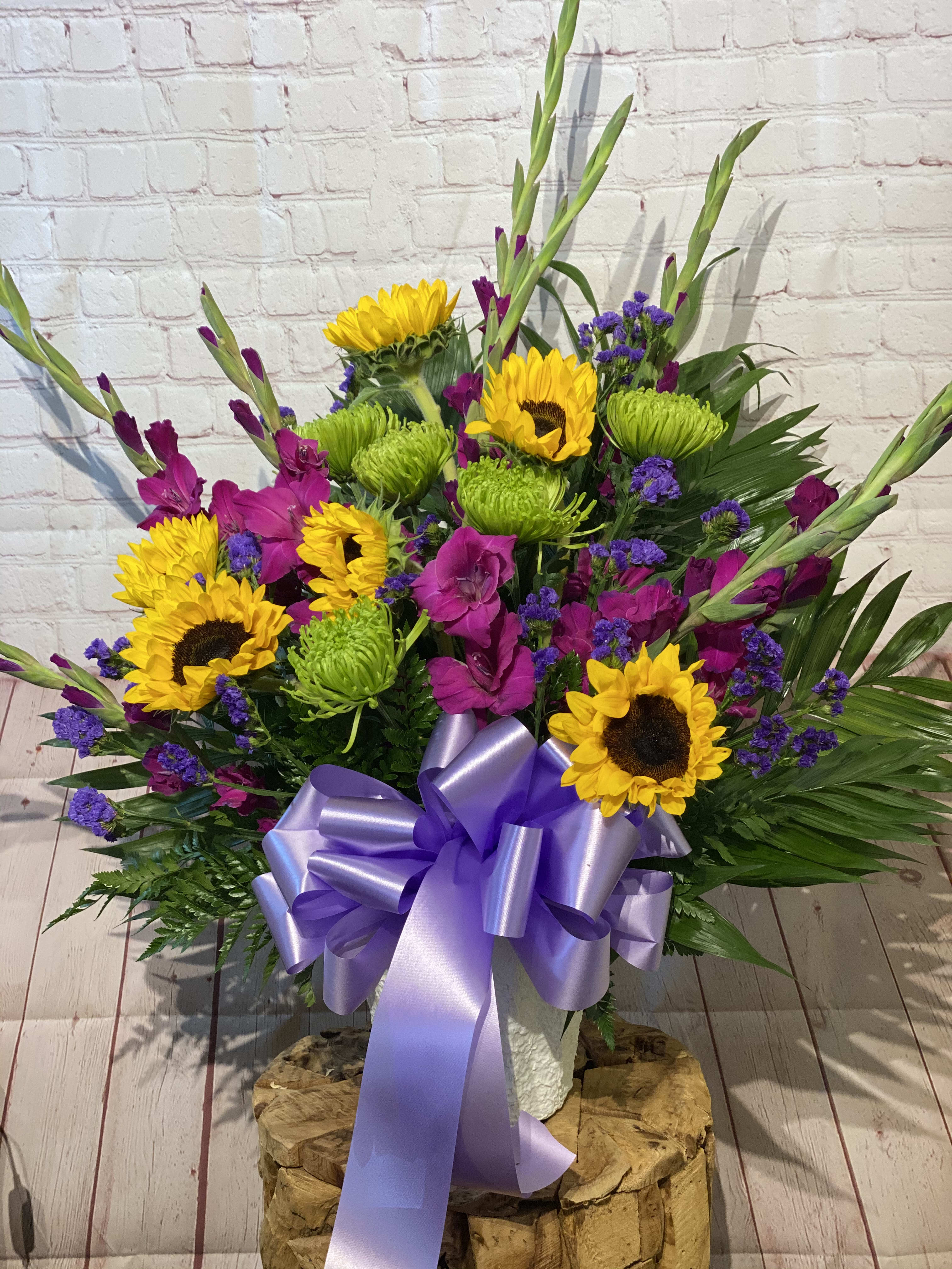 Bright mixed bouquet with sunflowers, purple flowers, and a lavender ribbon
