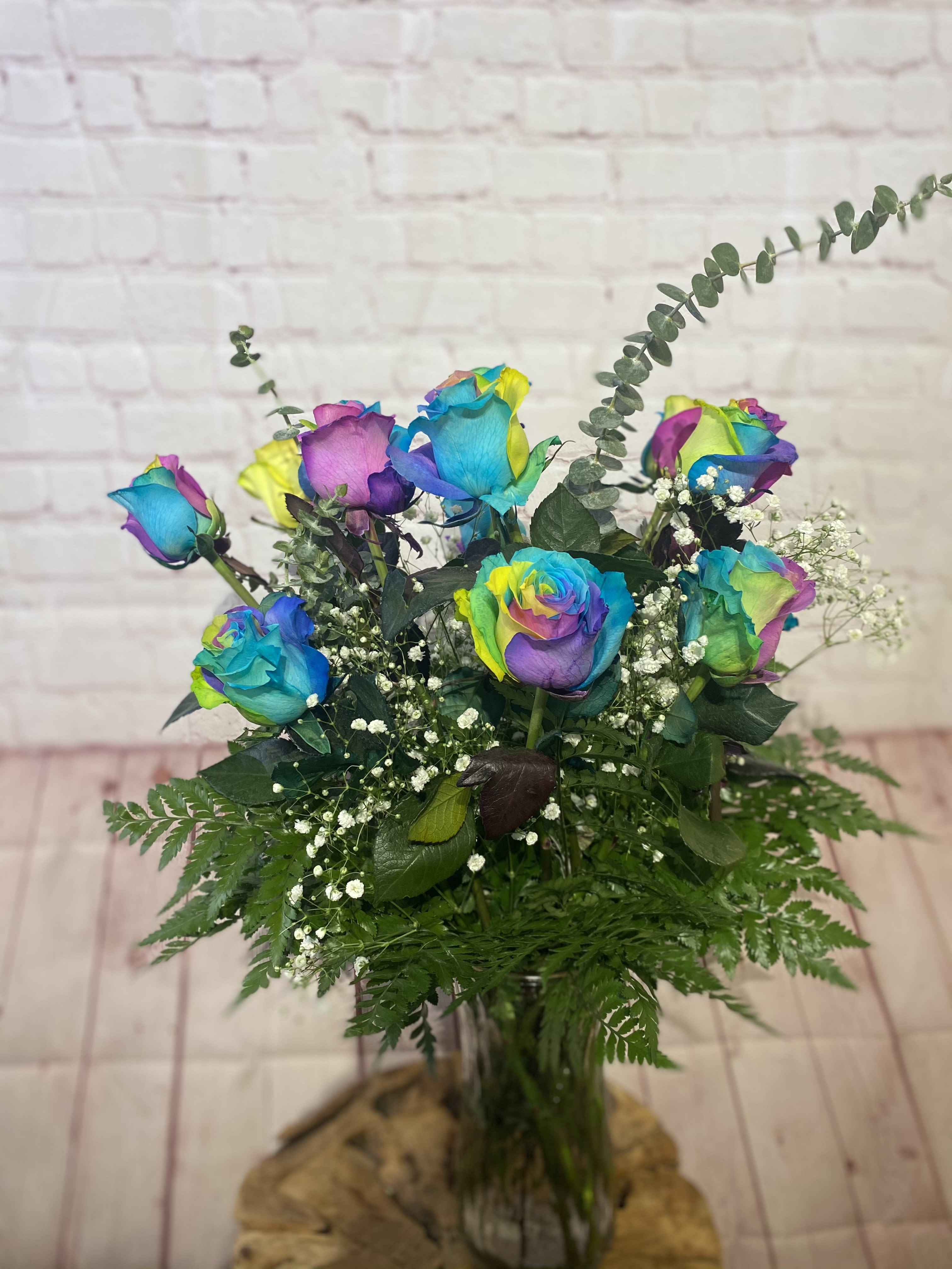 Bouquet of rainbow-colored roses in a glass vase