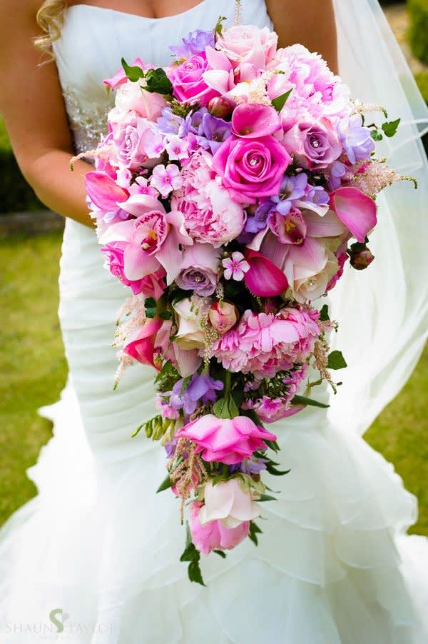 Bride holding a cascading bouquet of pink and purple flowers