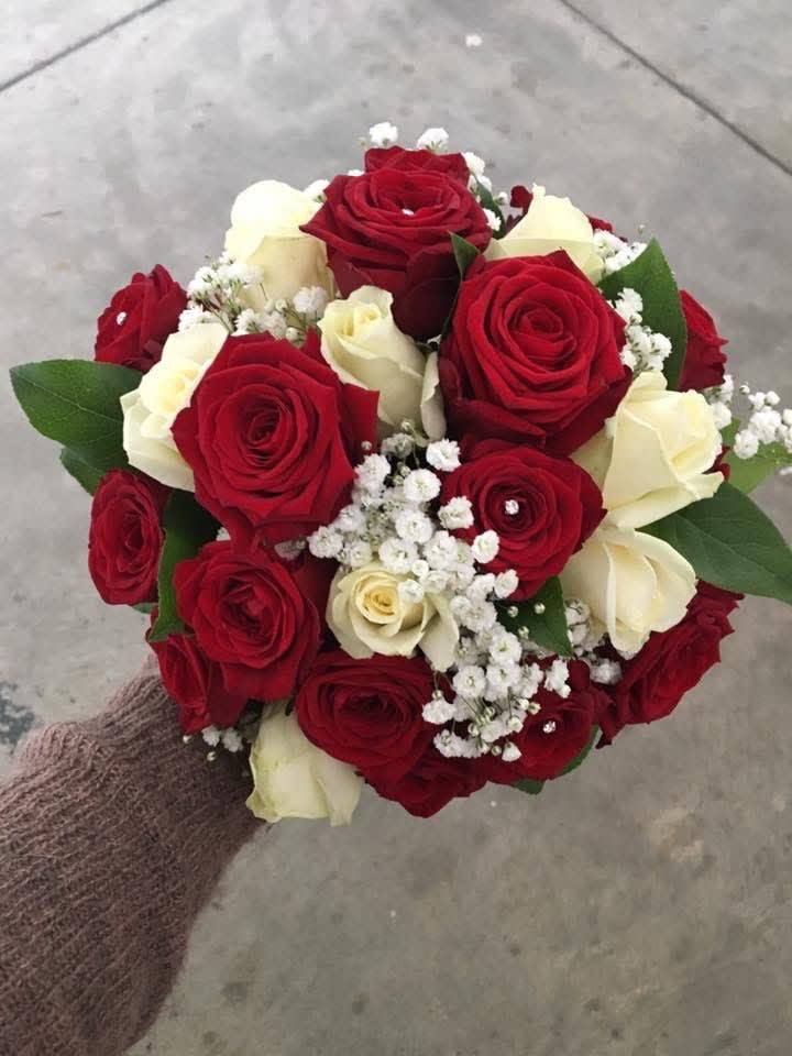 Handheld bouquet of red and white roses with baby's breath