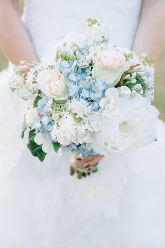 Bride holding a pastel bouquet of white, blue, and pale pink flowers