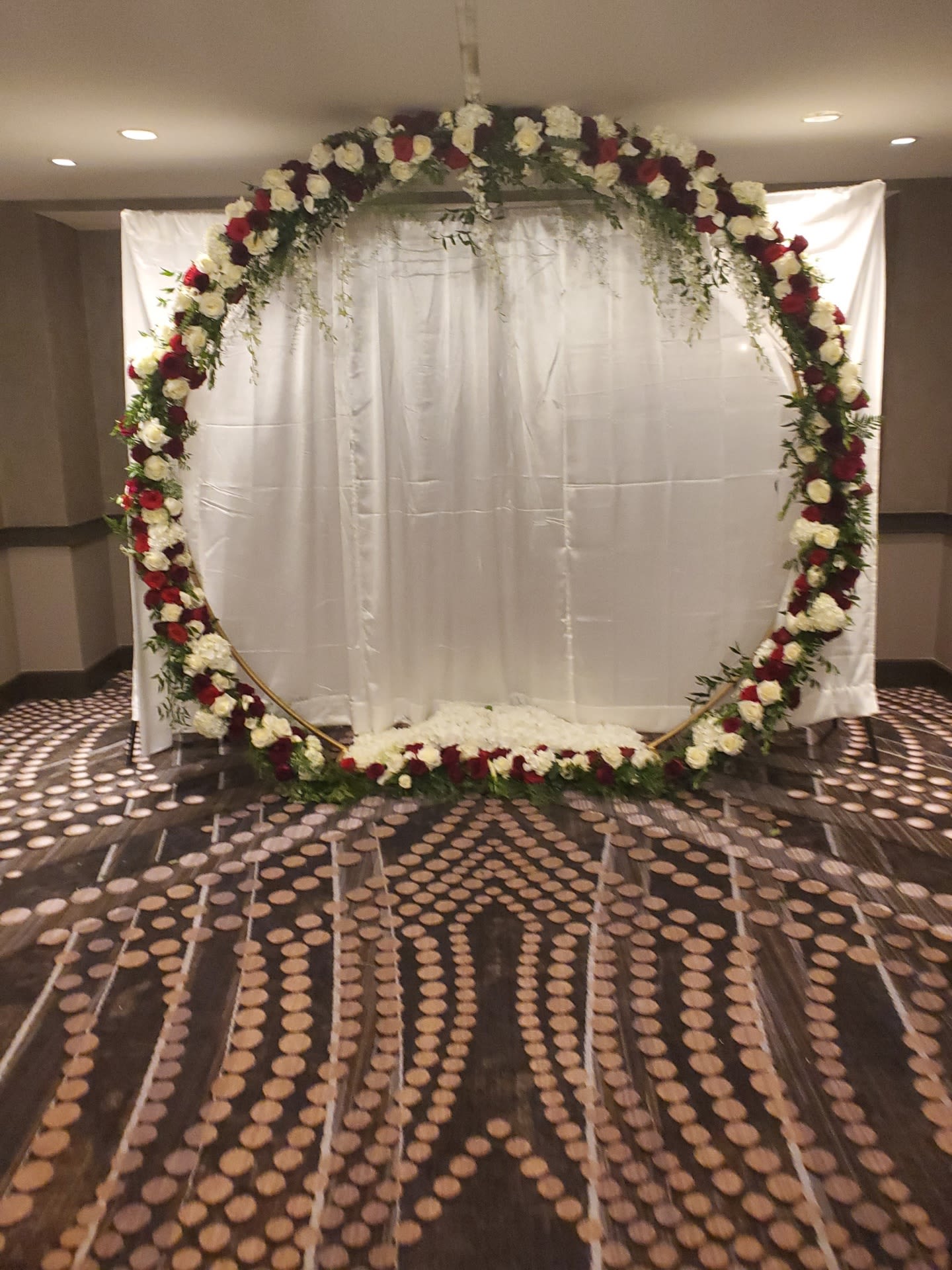 Large floral arch with red and white roses in front of a white backdrop