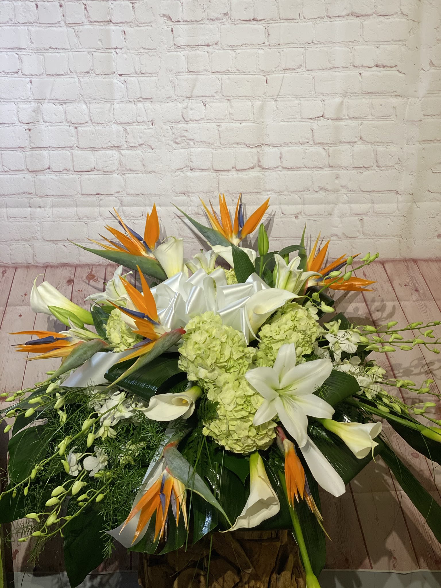 Large tropical floral arrangement with white lilies and orange bird-of-paradise