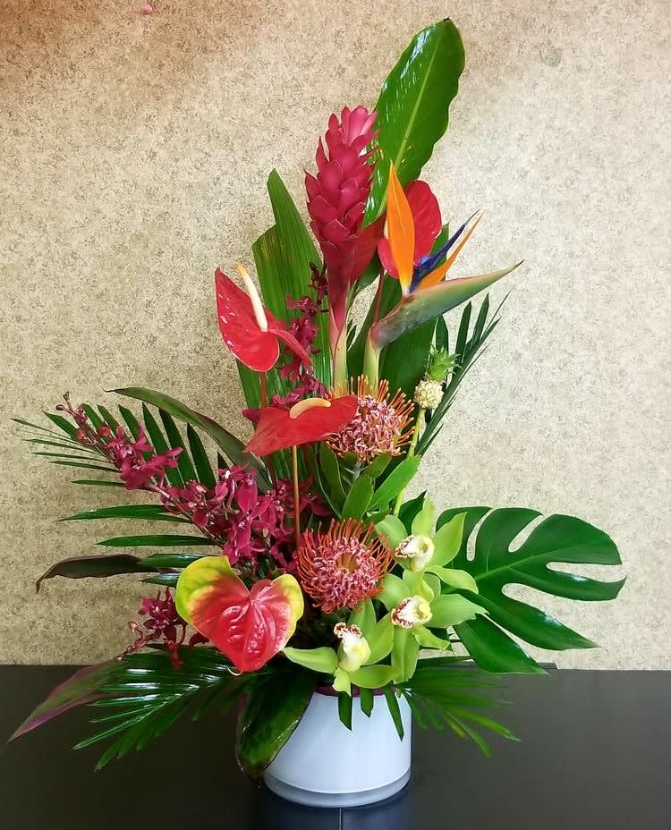 Tropical flower arrangement in a white vase with red and green blooms