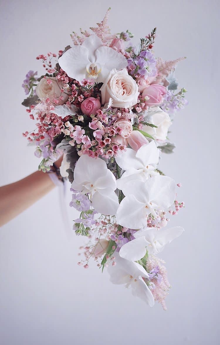 Cascade bouquet of white orchids, pale pink roses, and lavender flowers