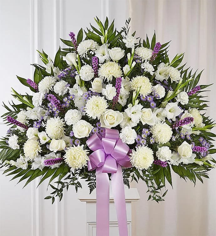 Large white floral spray with a lavender ribbon on a stand