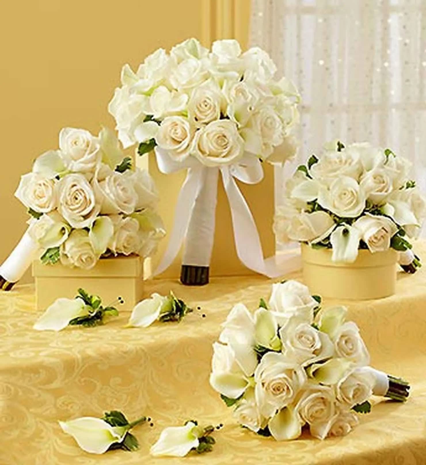 White rose and calla lily bouquets with ribbon on a gold table