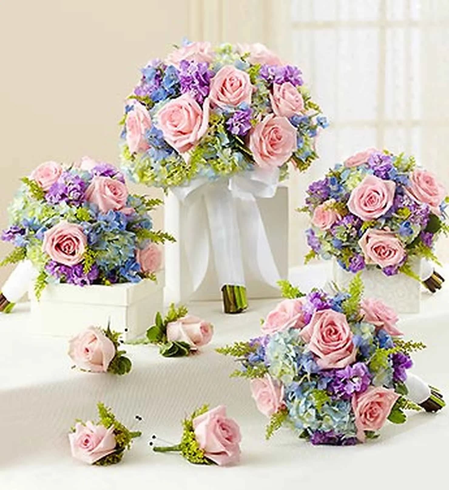 Pink rose bouquets with blue and purple flowers on white stands