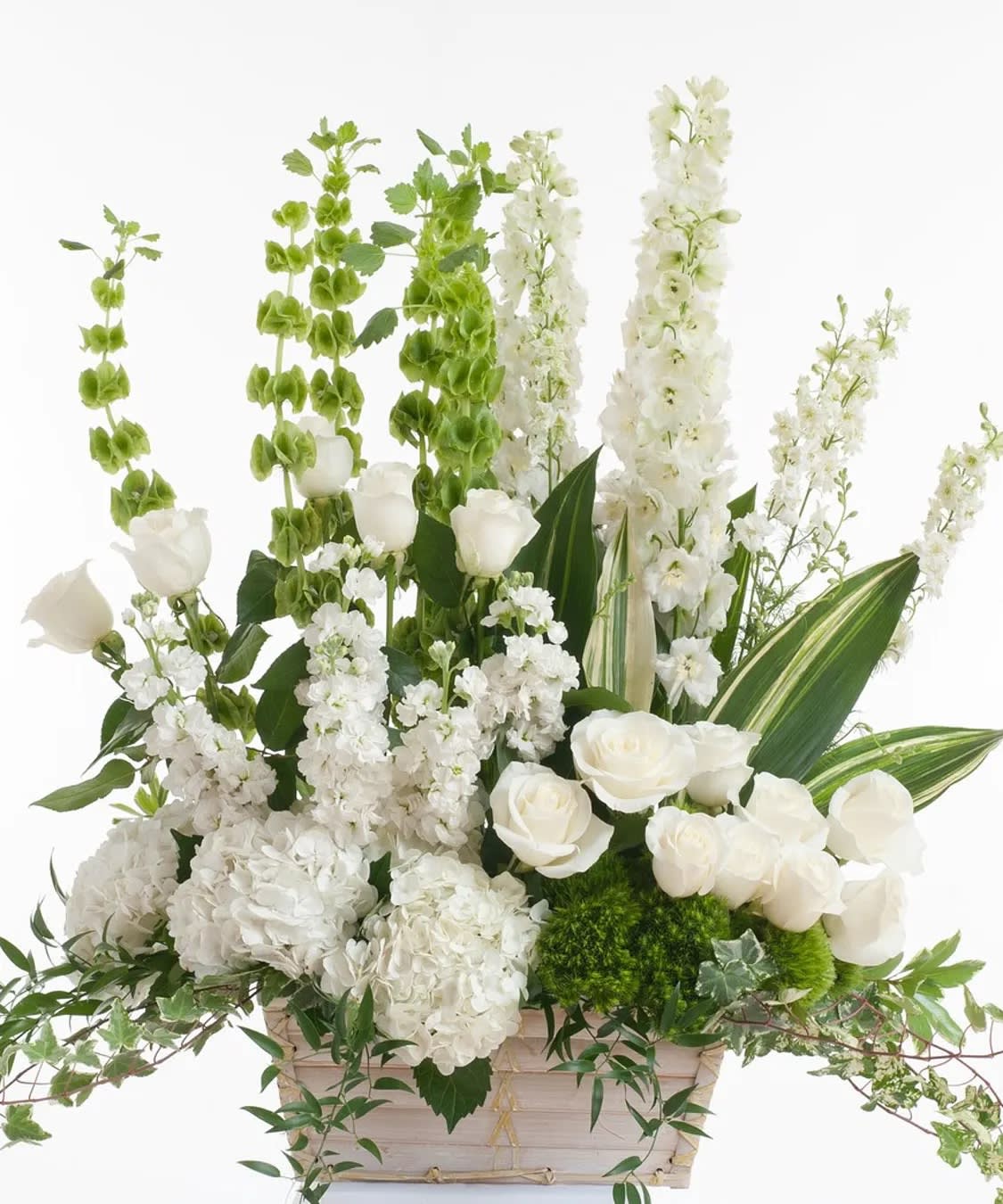 White floral arrangement in a pale basket with tall green and white spikes