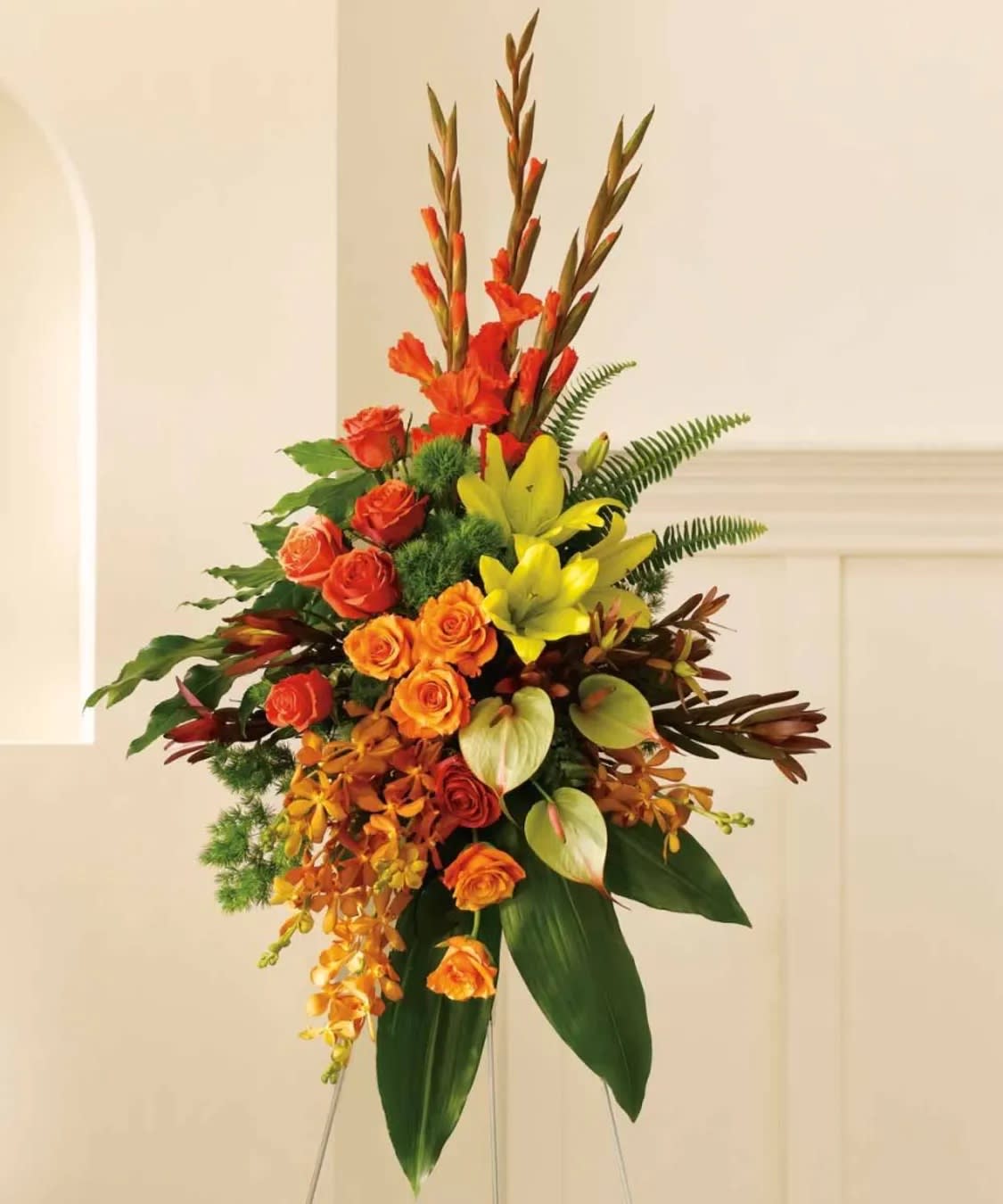 Tall floral arrangement with orange and yellow blooms on a stand