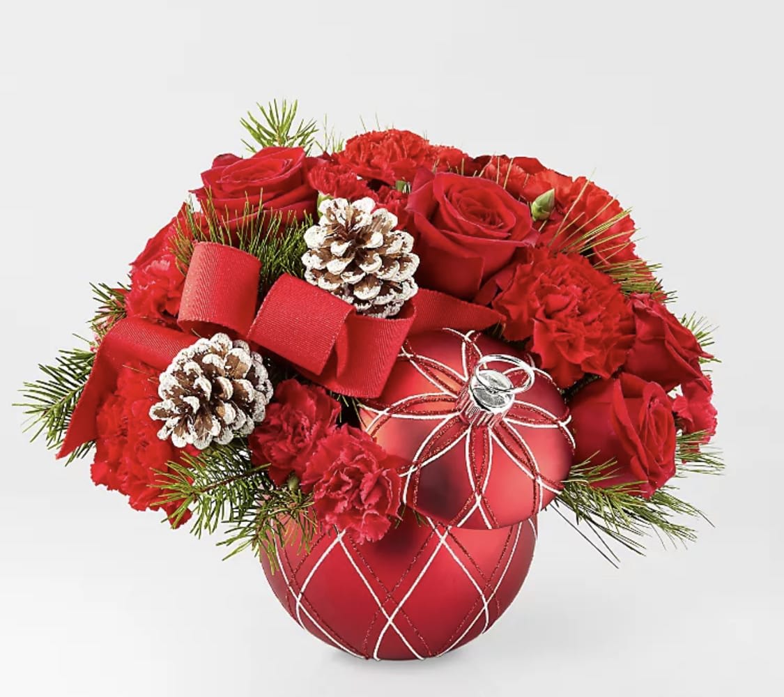 Red roses and carnations arranged with pinecones in a red ornament vase