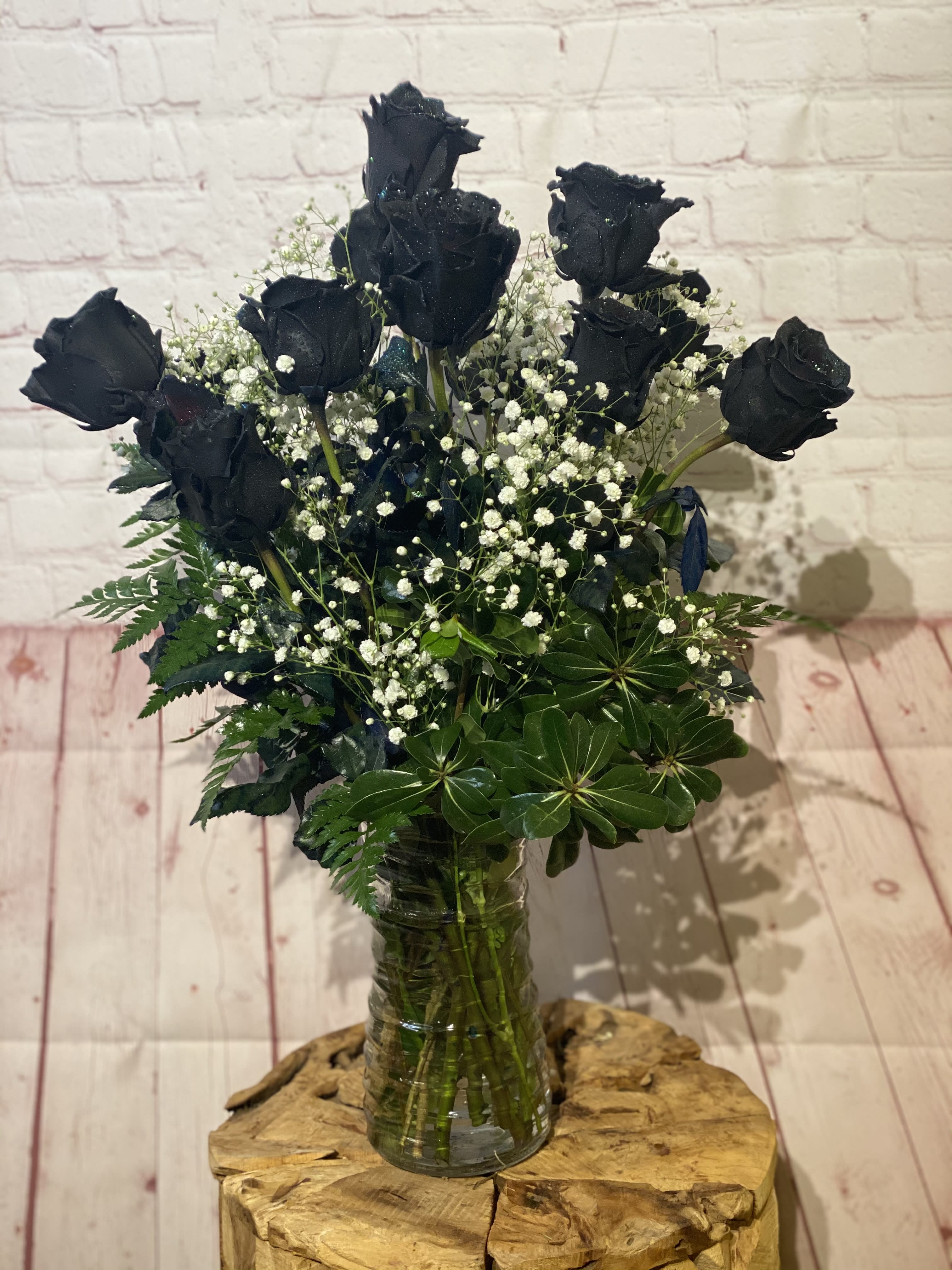 Bouquet of black roses with baby's breath in a glass vase