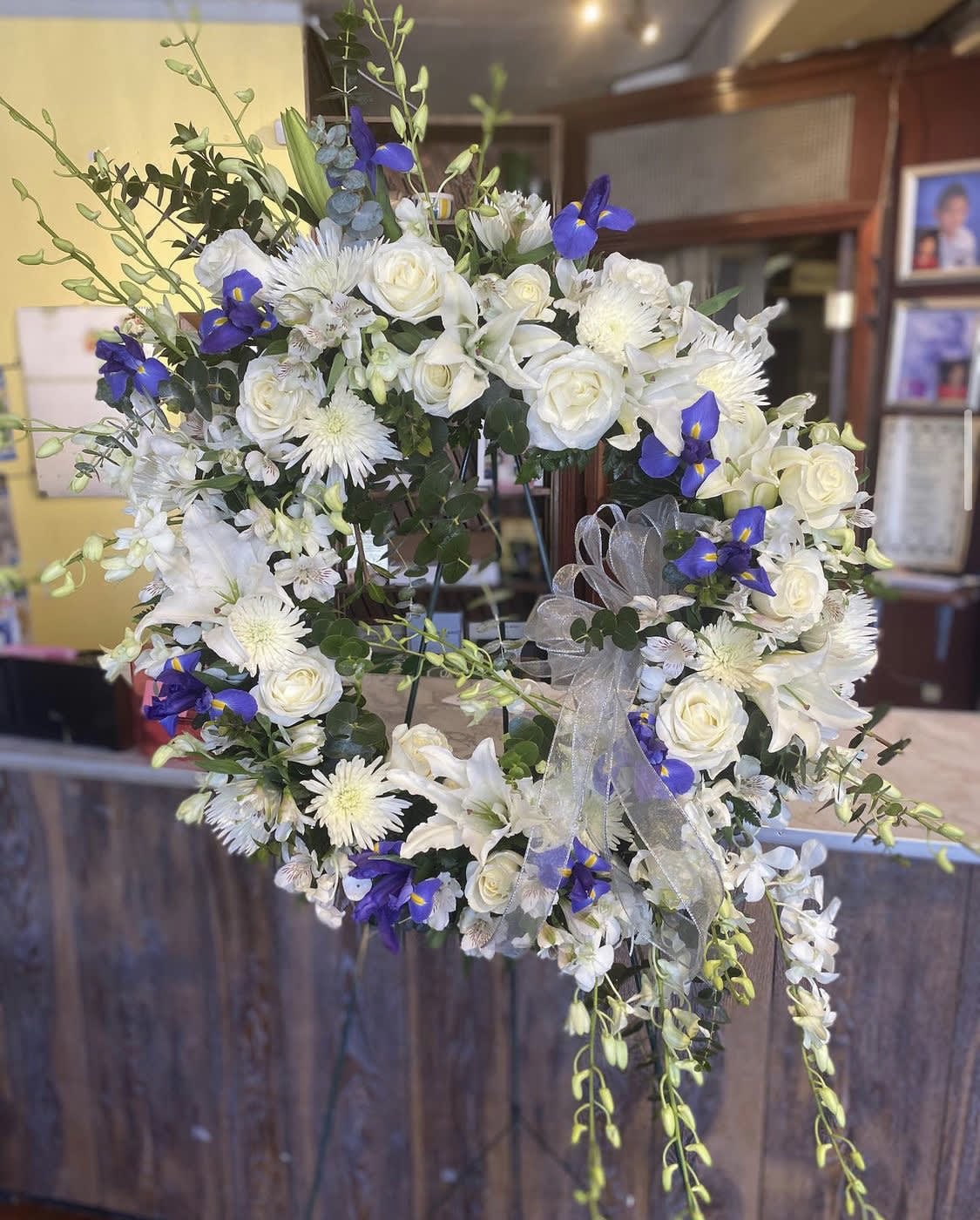 White floral wreath with blue accents and a sheer ribbon