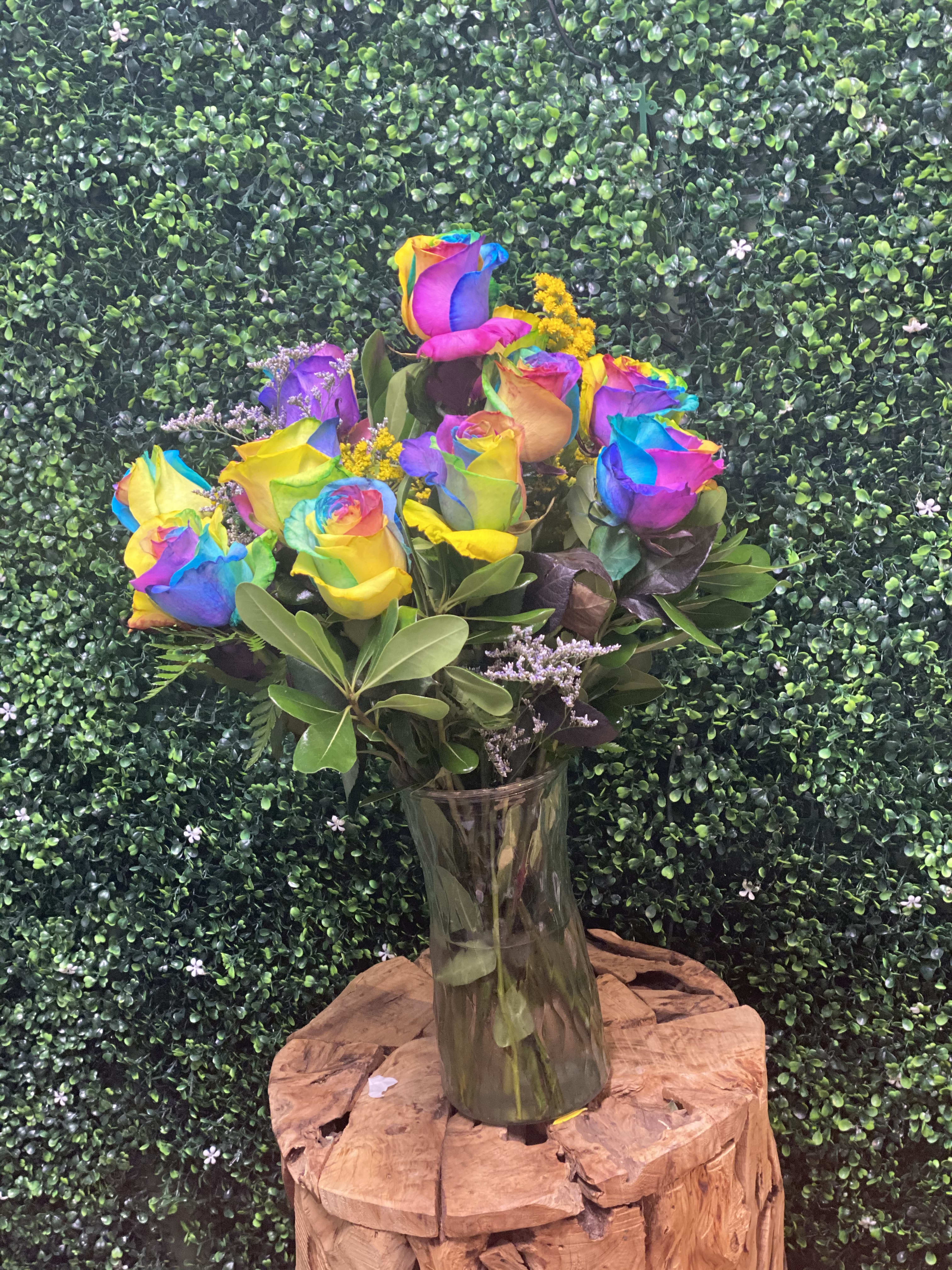 Rainbow-colored roses in a clear glass vase