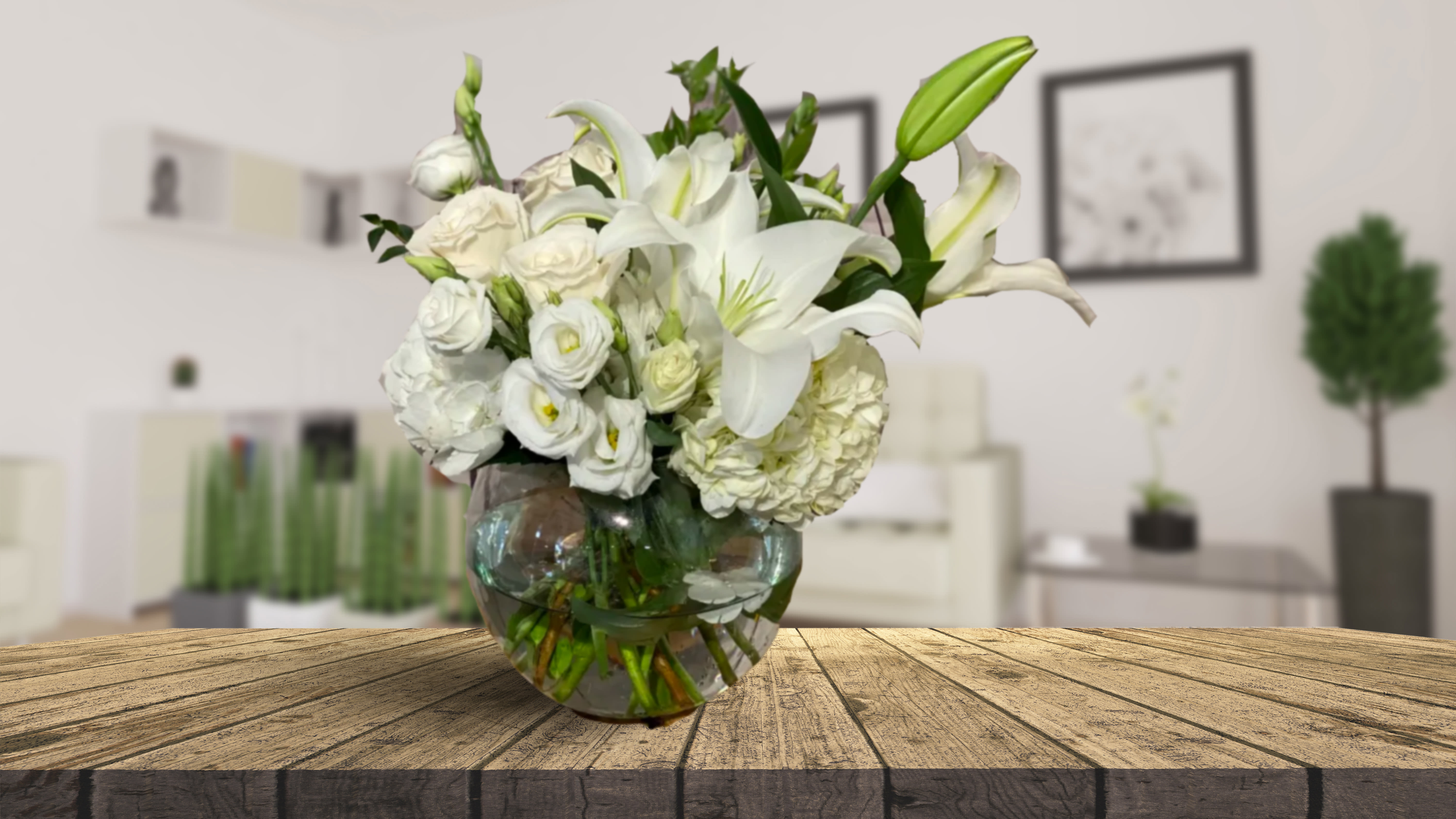 White lilies and roses arranged in a round glass vase