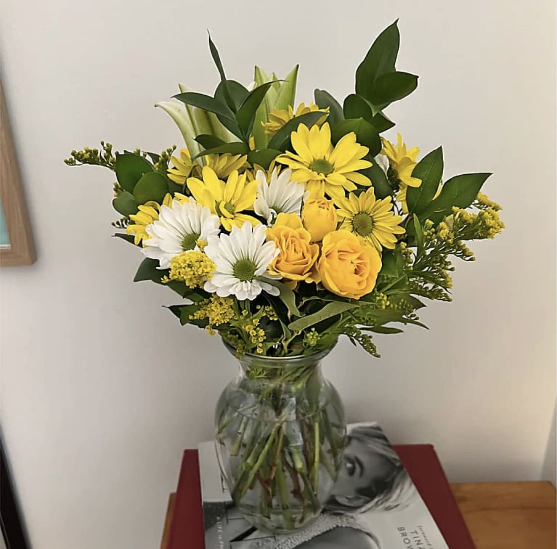 Yellow and white flowers arranged in a clear glass vase