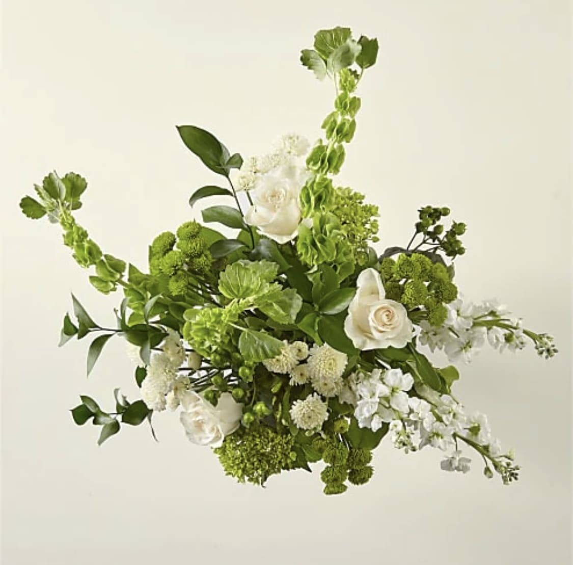 Green and white floral arrangement with roses and tall spiky blooms