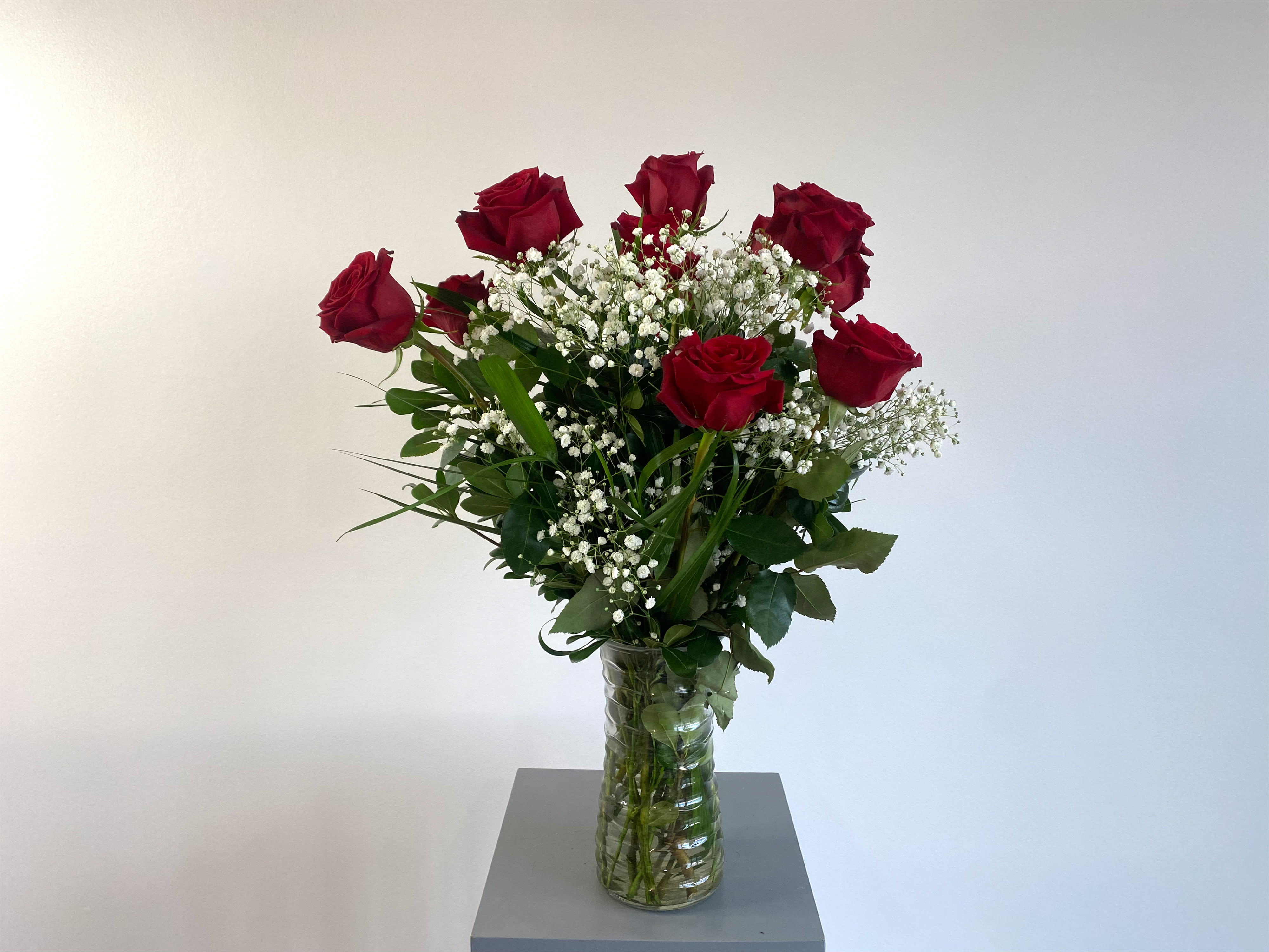 Red roses in a clear glass vase with baby's breath