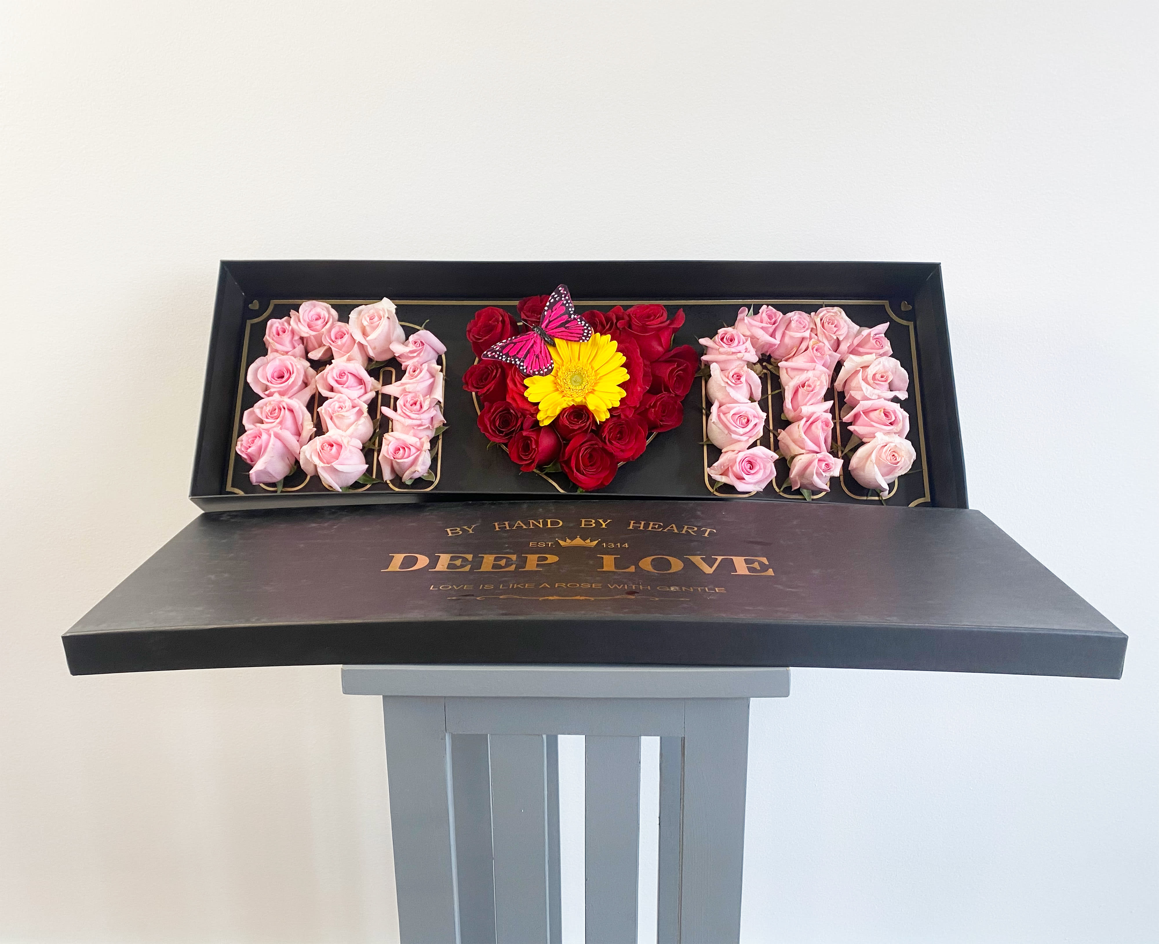 Heart-shaped rose box with pink and red roses and a yellow flower