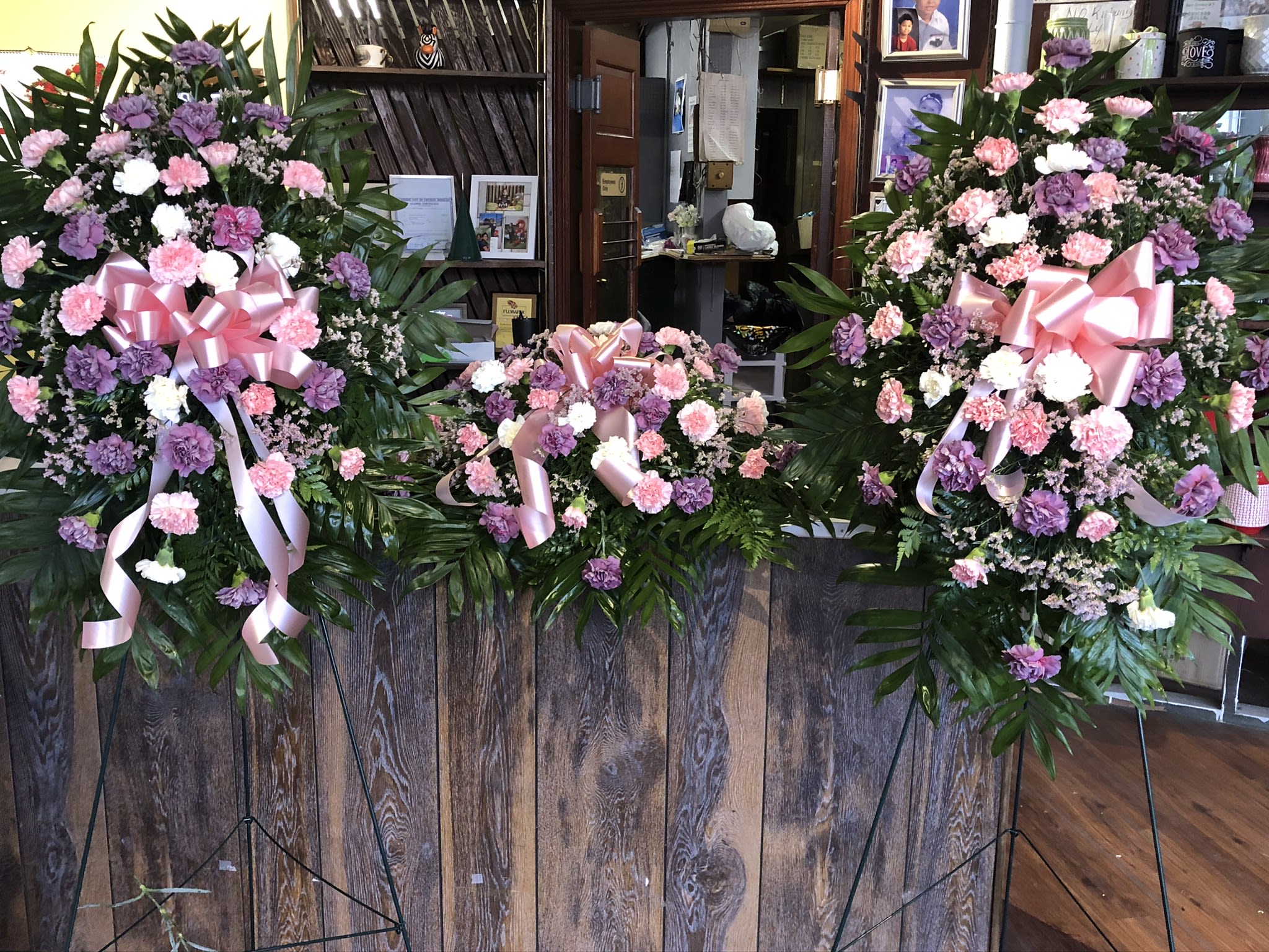 Three pink and purple standing floral sprays with ribbon bows