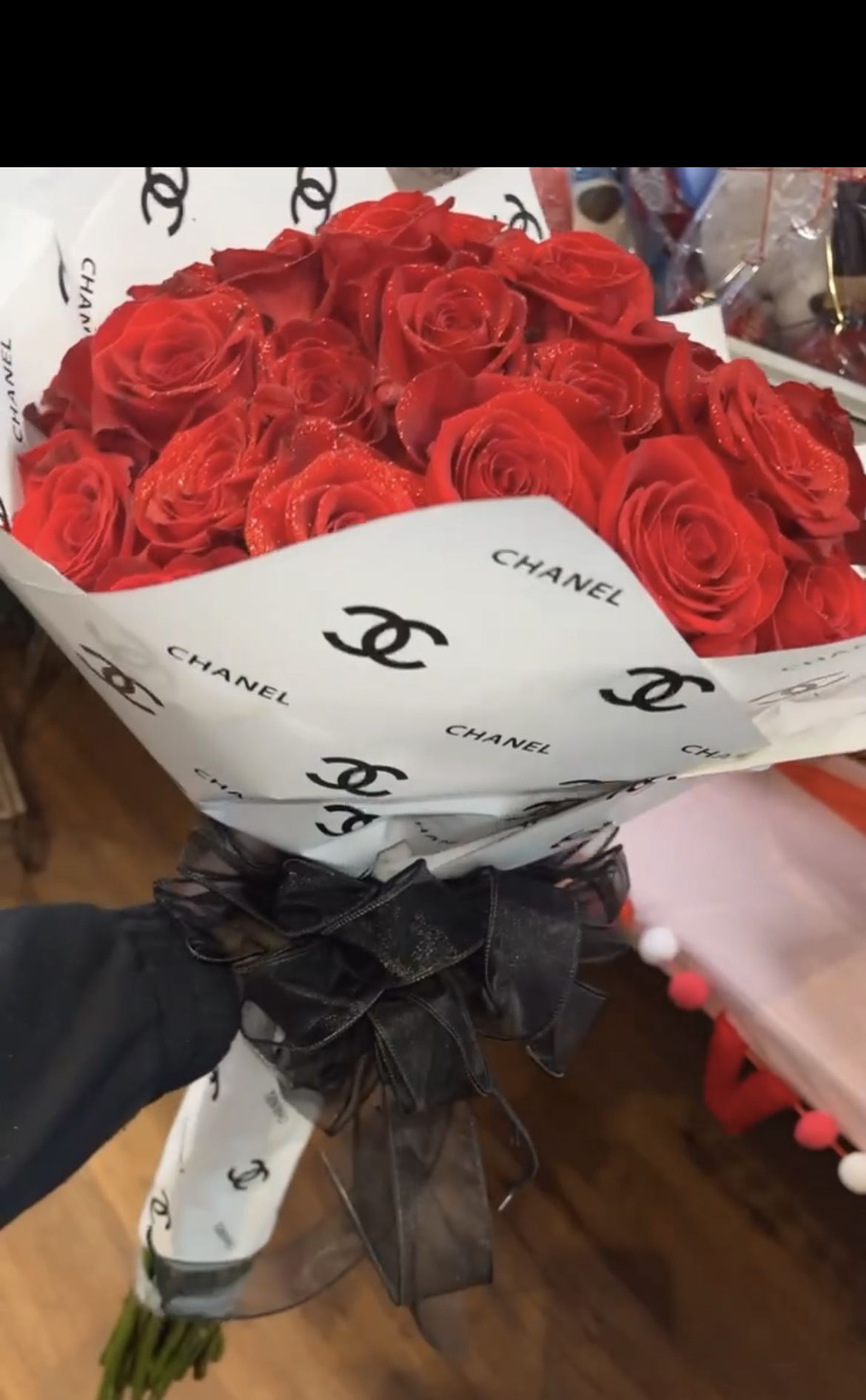 Bouquet of red roses wrapped in white Chanel paper with a black ribbon