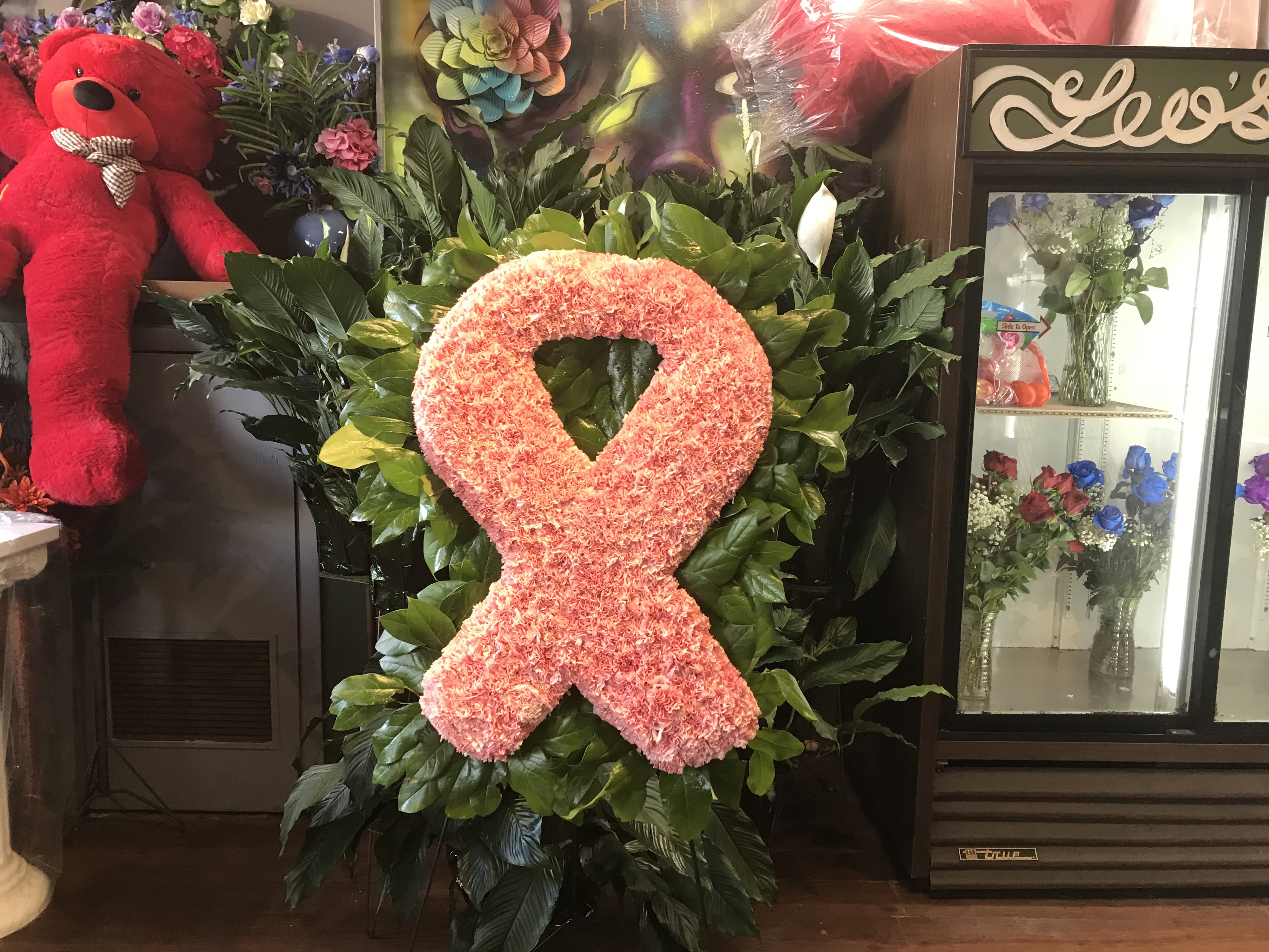 Pink floral awareness ribbon on a leafy standing display