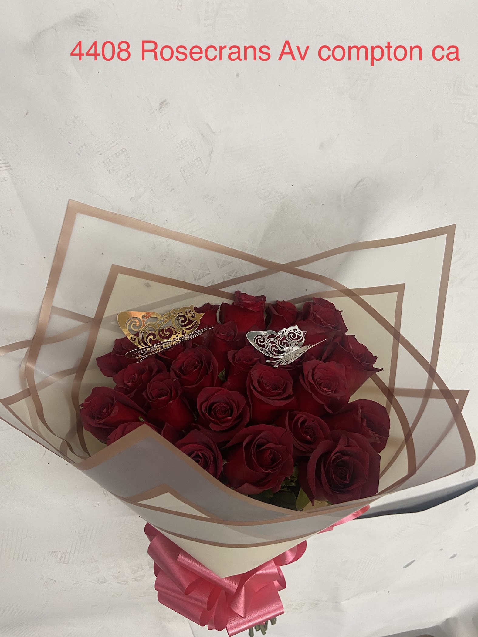 Bouquet of red roses wrapped in clear paper with a pink ribbon
