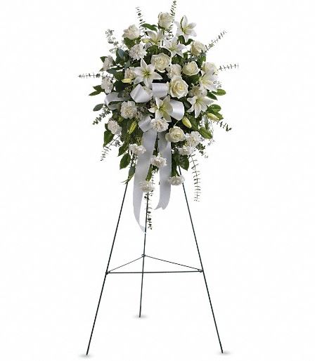 White floral standing spray on a metal easel with ribbon