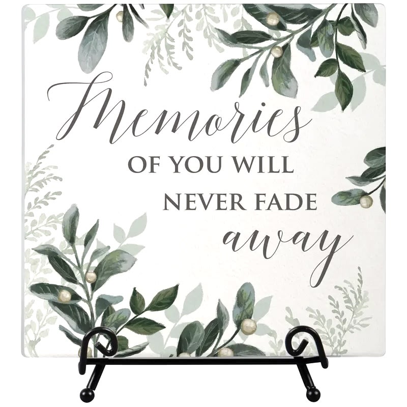 Memories Never Fade Easel Plaque - Our easel plaques are designed, printed, and packaged in the USA. Made of ceramic, these plaques come gift boxed and include the wire easel. W: 6"H: 6" If sending to a funeral home or memorial service, we will deliver this so it can be dislayed on the easel during the visitation and service. If delivered to a residence, this will be packaged in tissue paper and delived in our signature kraft paper bag with a ribbon
