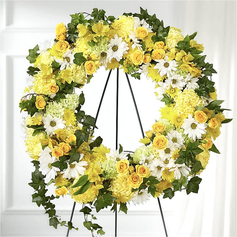 Golden Remembrance Wreath - GOLDEN REMEMBRANCE WREATH Whether yellow was their favorite color or it captures the essence of their radiance, a ring of bright blooms thoughtfully displays your sentiment. Our Golden Remembrance Wreath is composed of spray roses, daisy pompons, carnations and more. Each flower is selected to beautifully accent one another and the love you are sending.  Please Note: The bouquet pictured reflects our original design for this product. While we always try to follow the color palette, we may replace stems to deliver the freshest wreath possible  Approximately 24" diameter