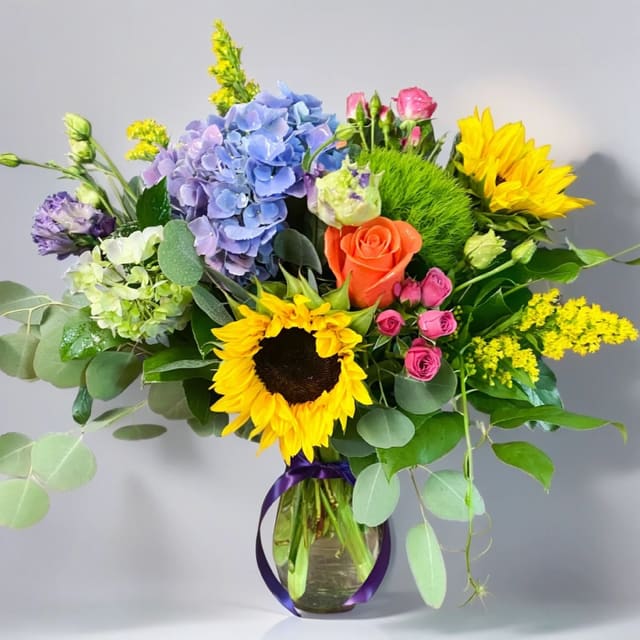 Sunshine Blooms Bouquet - Brighten someone's day with Hignight Florist’s Sunshine Blooms Bouquet! Featuring gorgeous hydrangeas, vibrant orange roses, delicate pink spray roses, and cheerful sunflowers, this bouquet is the perfect way to send a ray of sunshine to someone special. Spread love and joy with these beautiful blooms from Hignight Florist. Local flower delivery to the Quad Cities area is a convenient and timely service offered by our flower shop. We take pride in delivering beautiful floral arrangements to Davenport, Bettendorf, Rock Island, Moline, East Moline, Silvis, Hampton, Colona, Carbon Cliff, Coal Valley, and Milan. Whether you want to surprise a loved one or brighten someone's day, our efficient delivery service ensures your flowers arrive fresh and vibrant. Experience the joy of gifting flowers with our reliable local delivery service in the Quad Cities area.