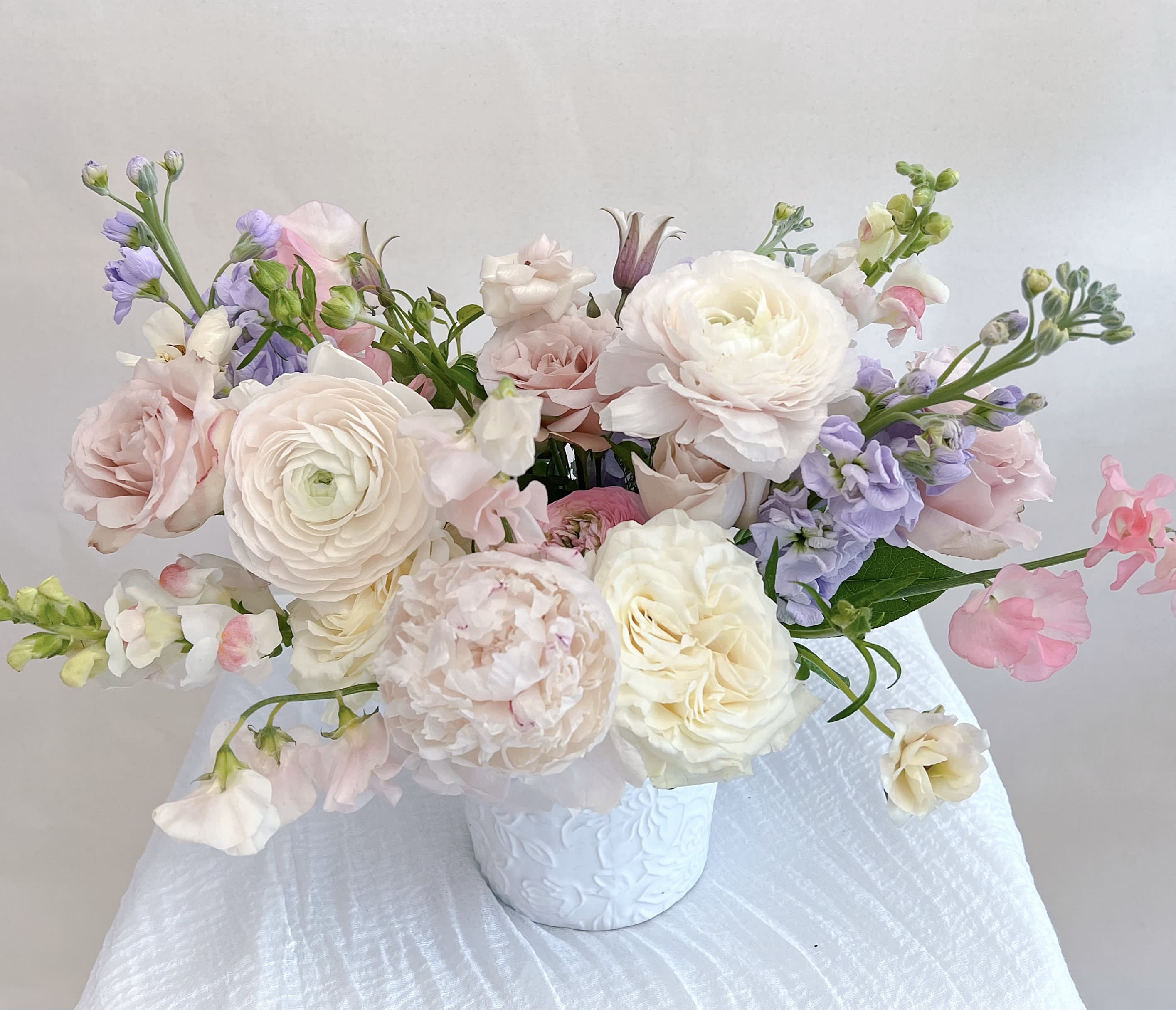 Pastel bouquet of roses and ranunculus in a white vase