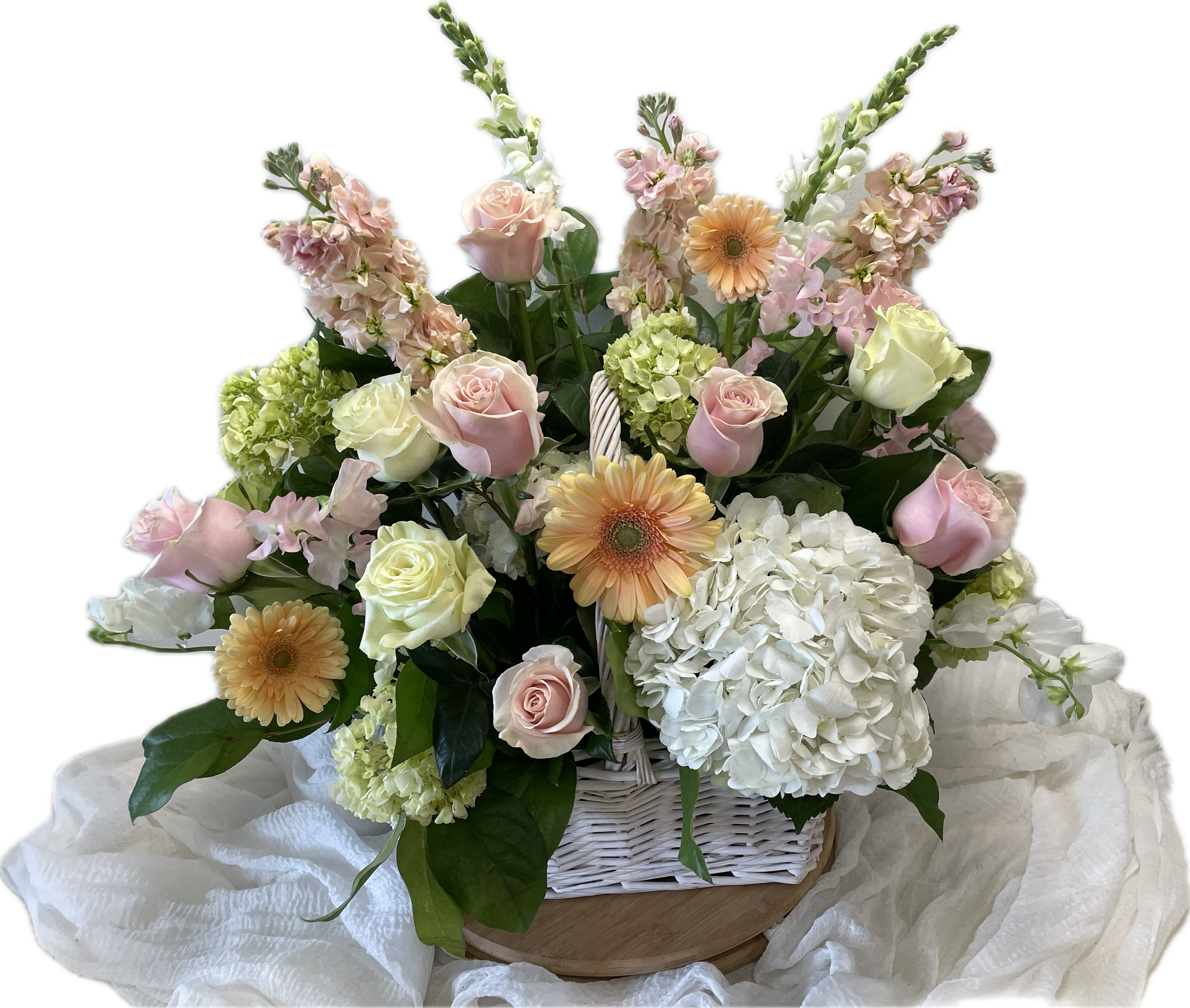 Pastel roses, gerbera daisies, and hydrangeas in a white basket