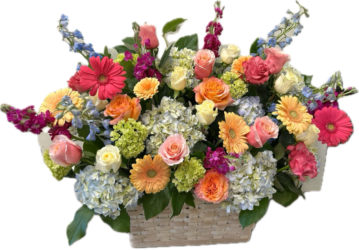 Mixed bouquet in a woven basket with roses, gerbera daisies, and hydrangeas