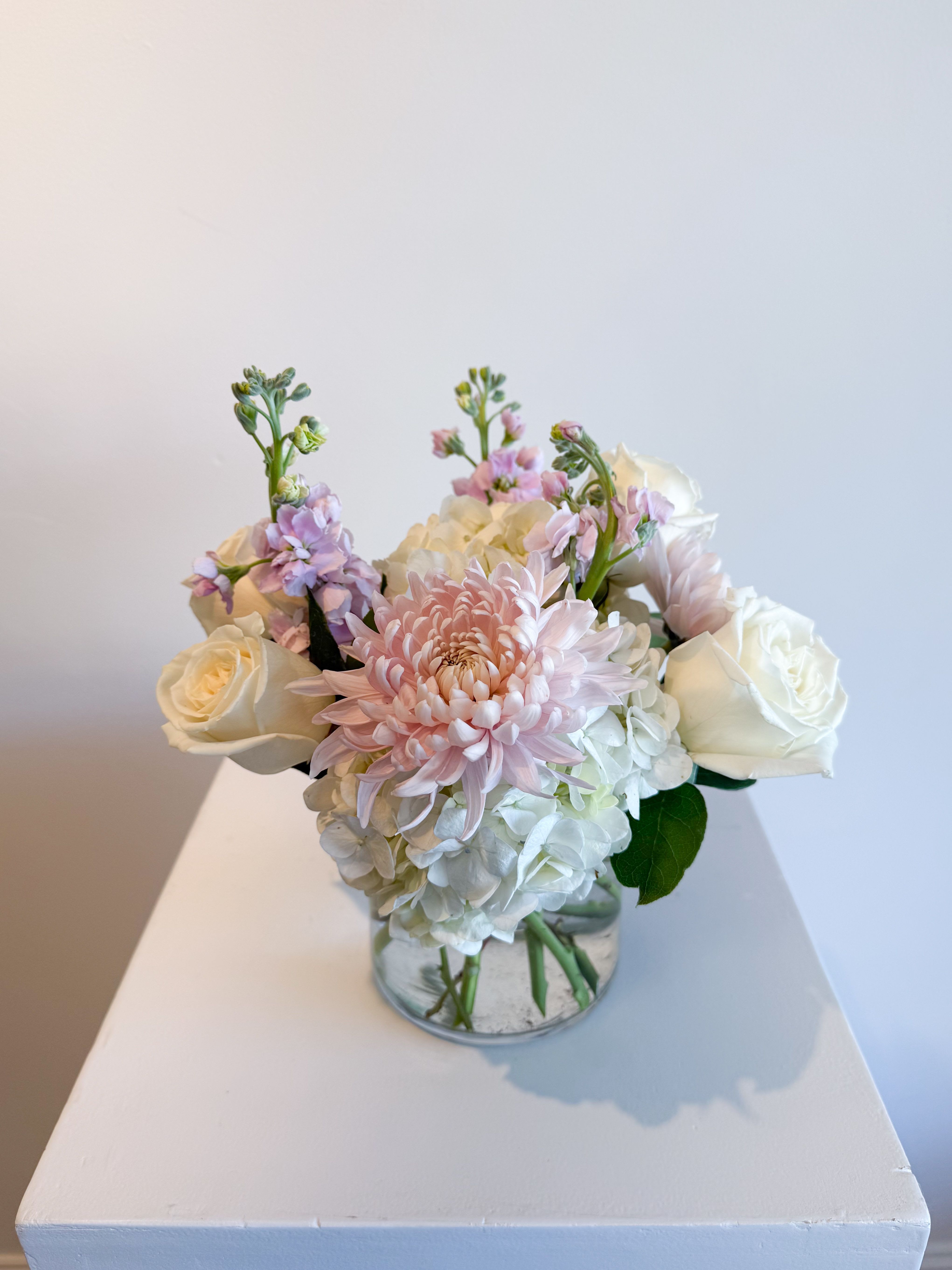 Pink and white flowers arranged in a clear glass vase