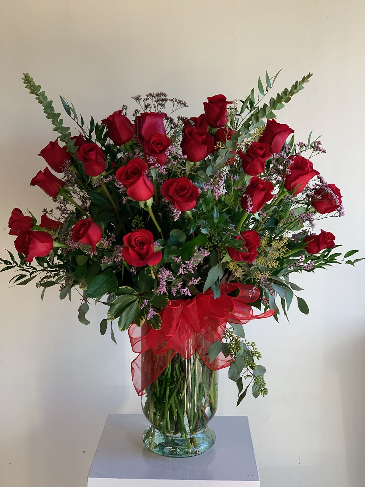Bouquet of red roses in a glass vase with a red ribbon