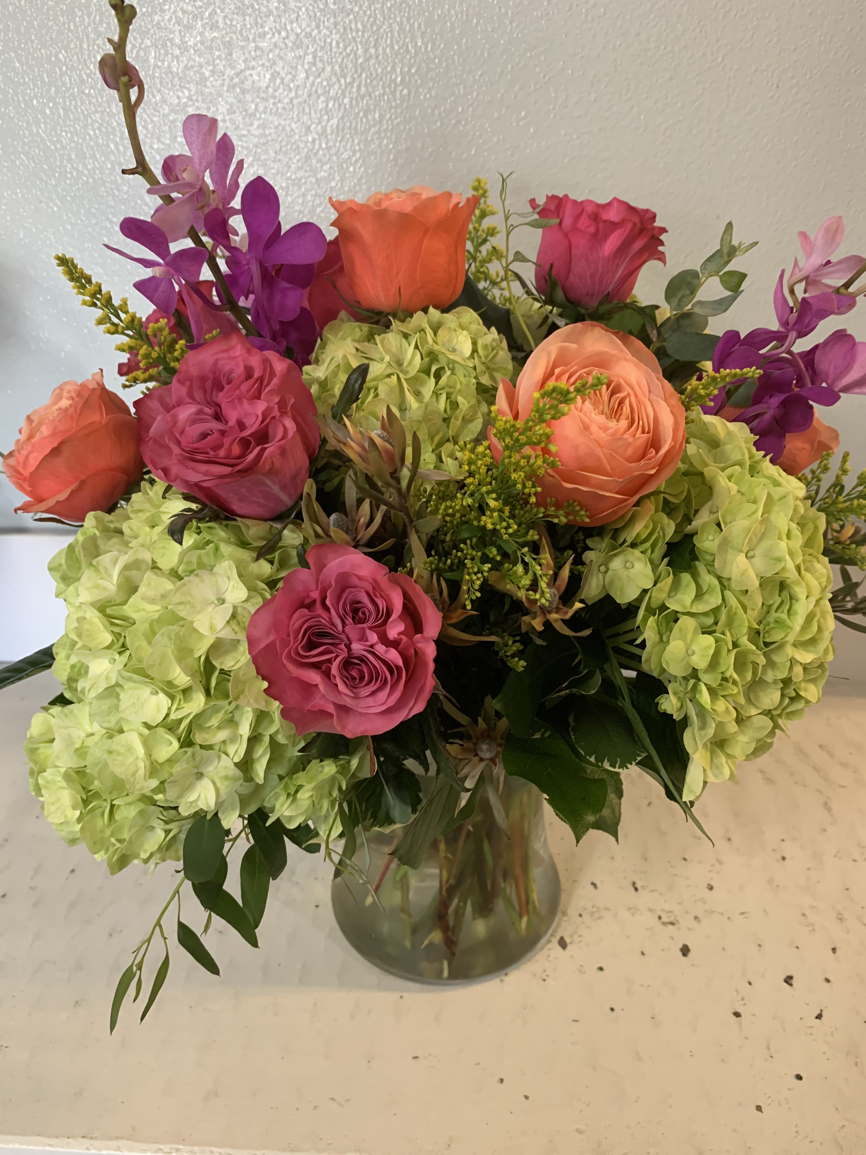 Bouquet of pink and orange roses with green hydrangeas in a glass vase