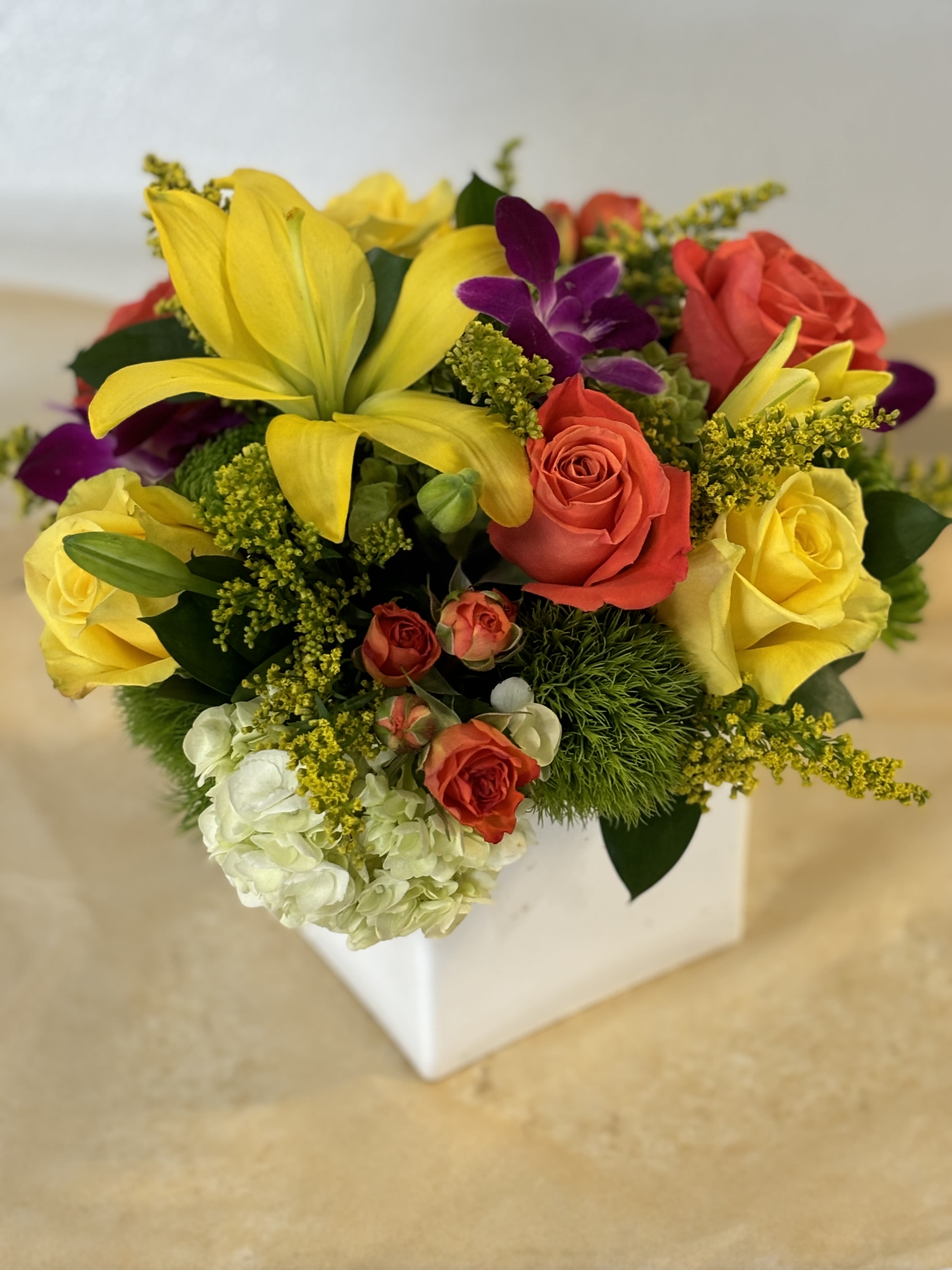 Mixed bouquet with yellow lilies, roses, and purple orchids in a white box