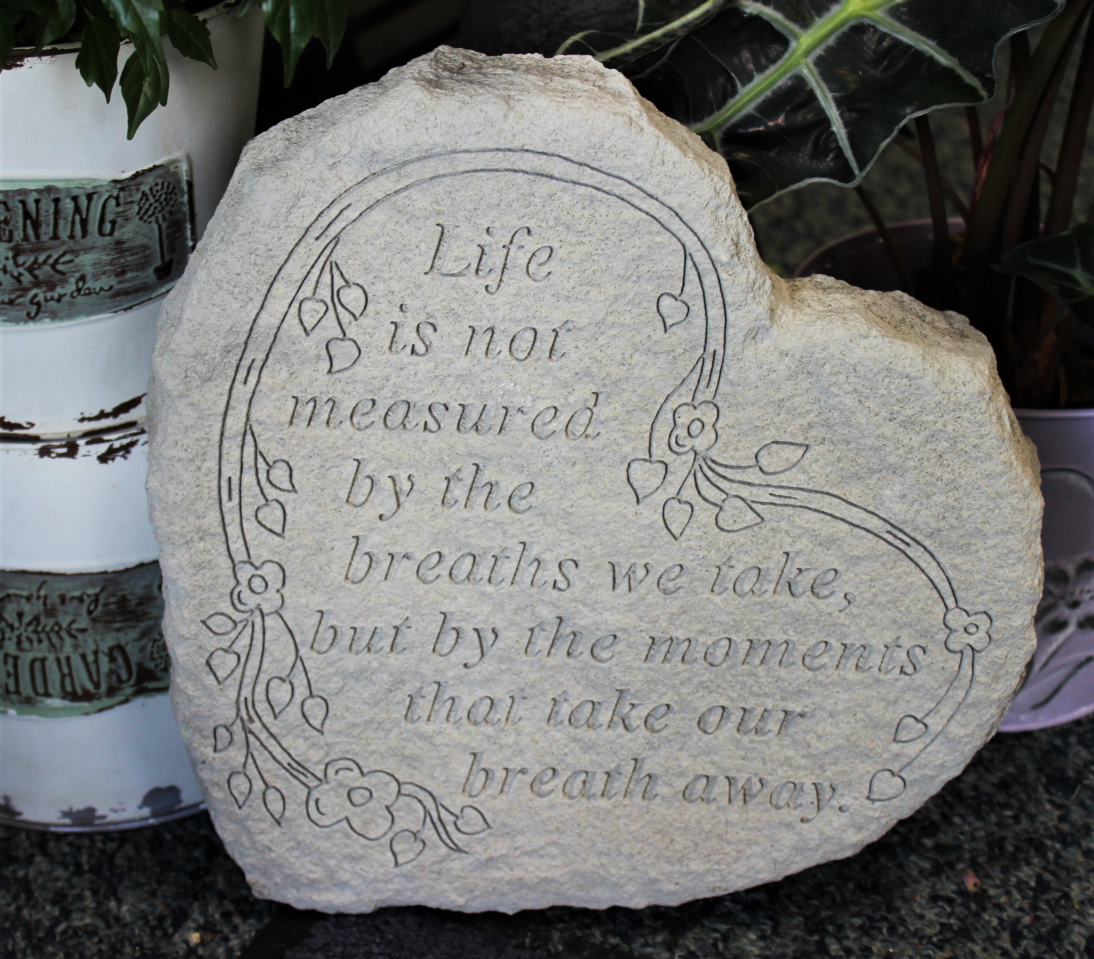 Engraved decorative stone with a floral border and quote