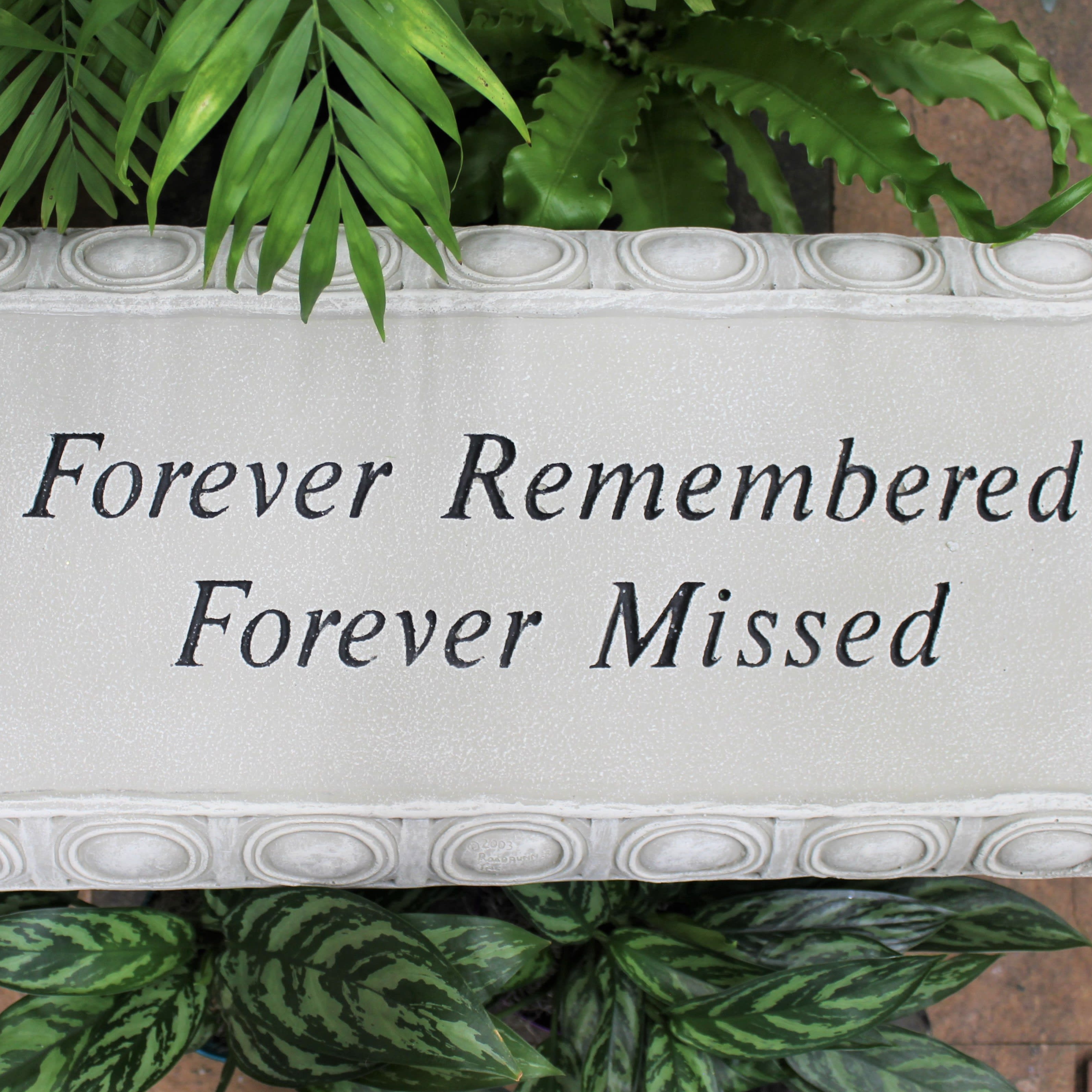 Memorial plaque with the words Forever Remembered Forever Missed surrounded by green plants