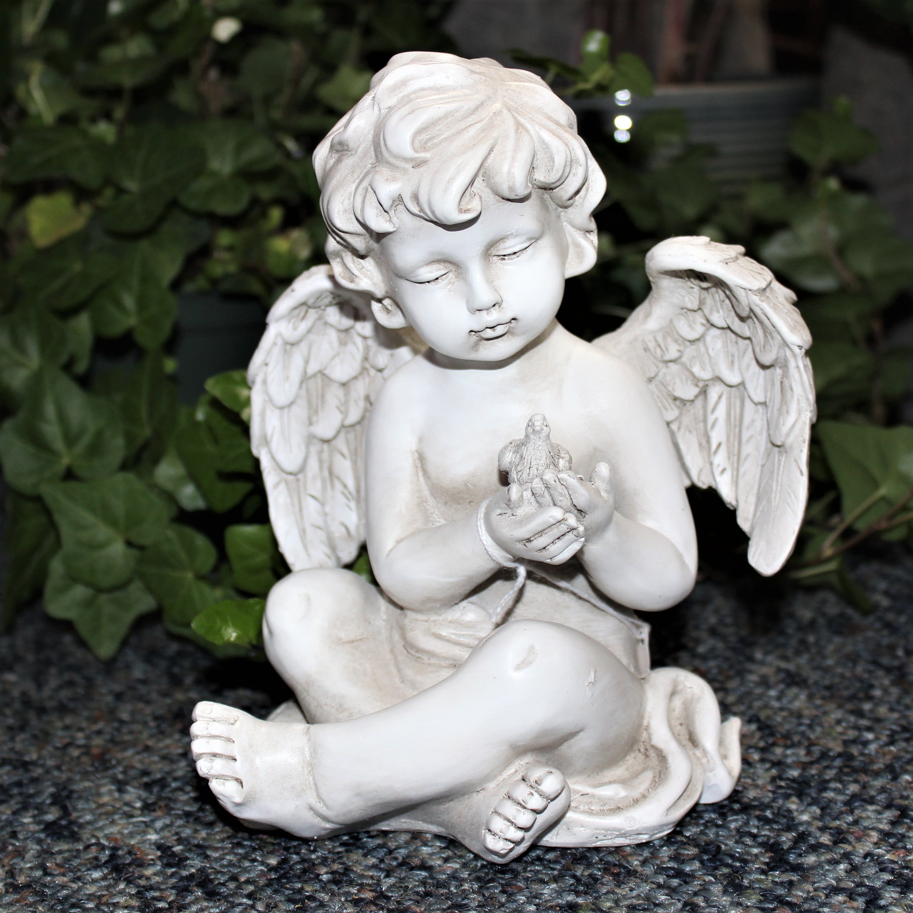 White angel figurine holding a small bird