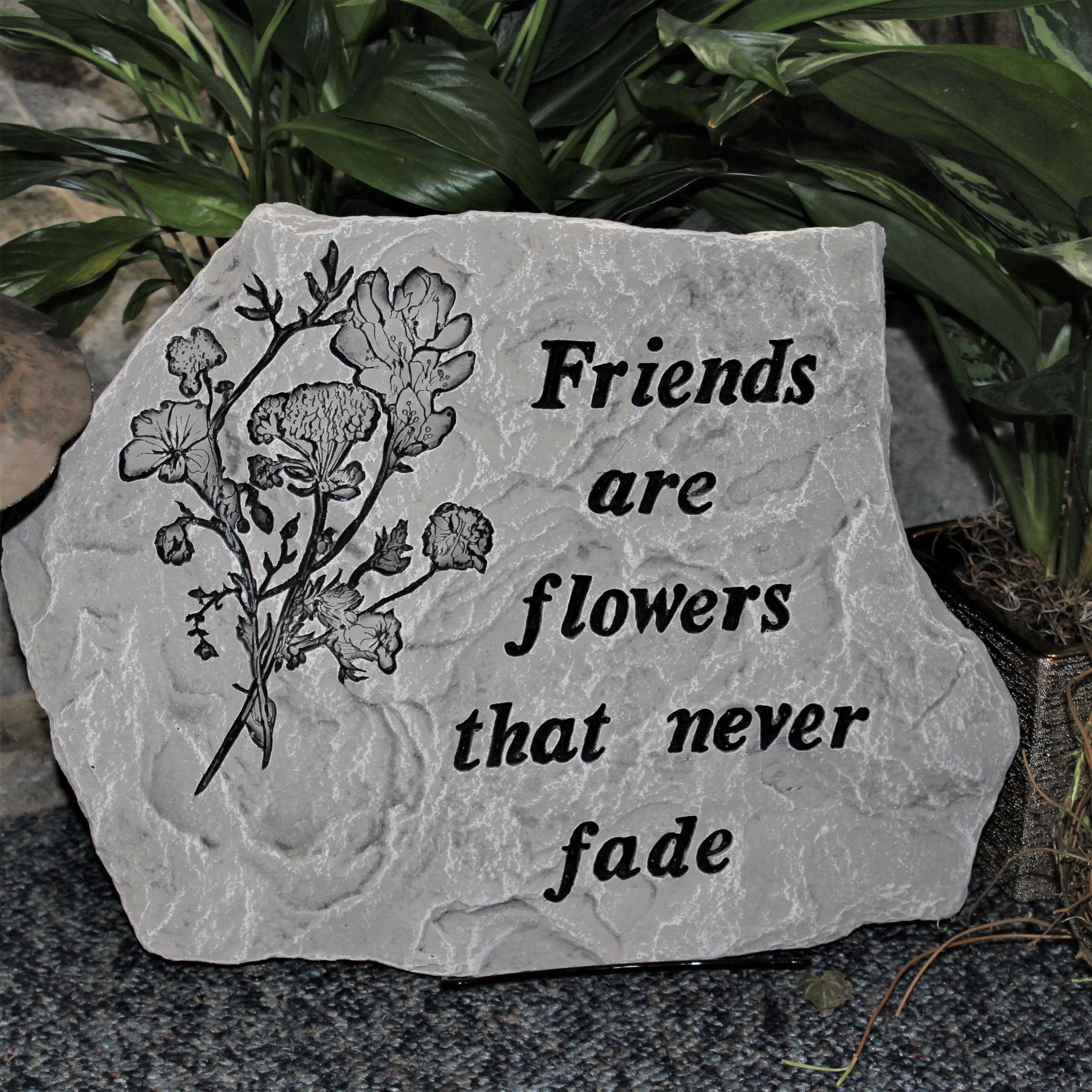 Decorative stone plaque with flowers and the words Friends are flowers that never fade