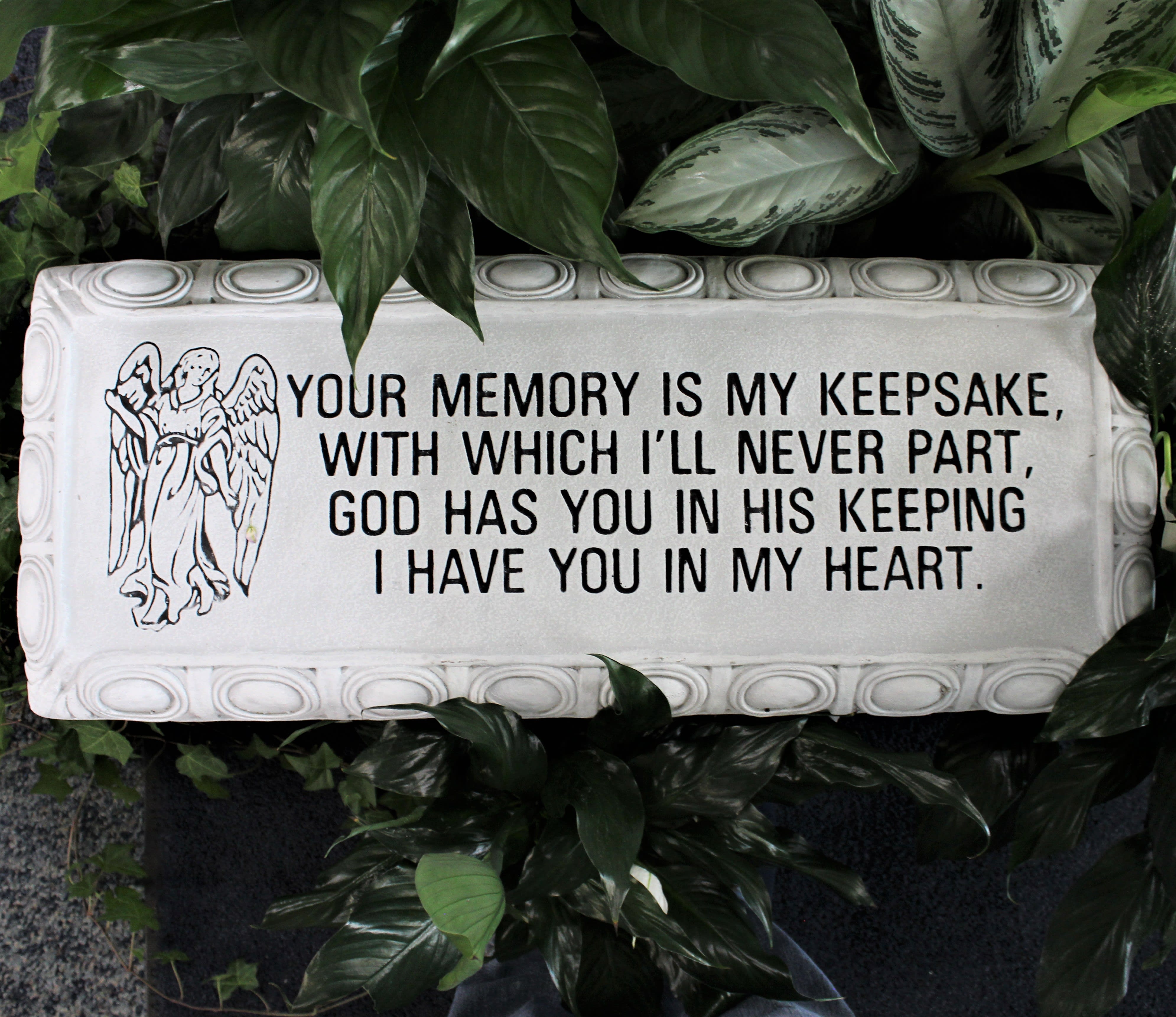 Memorial plaque with an angel and sympathy message surrounded by foliage