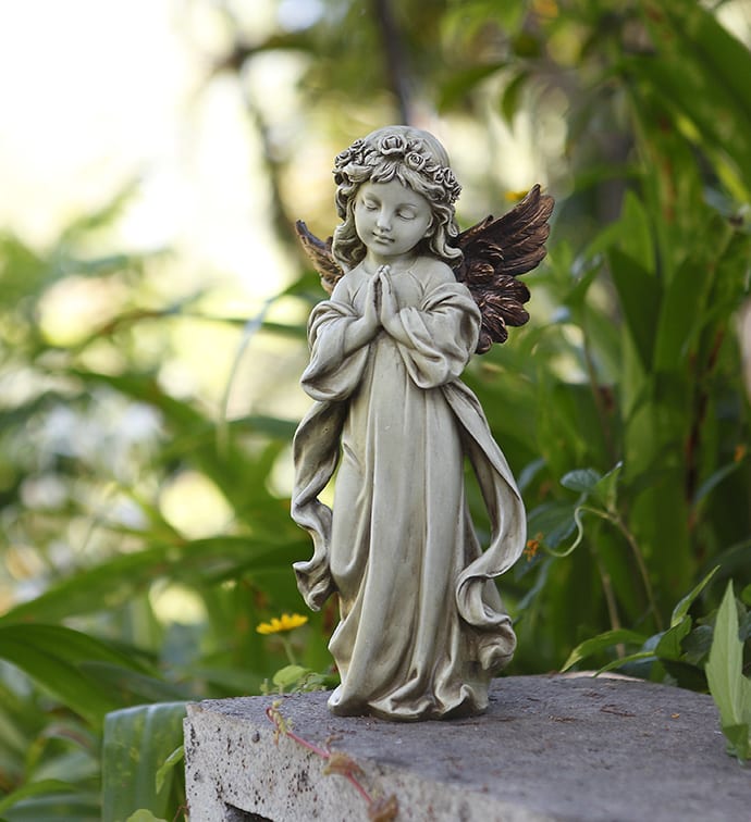 Small angel statue with folded hands on a stone surface