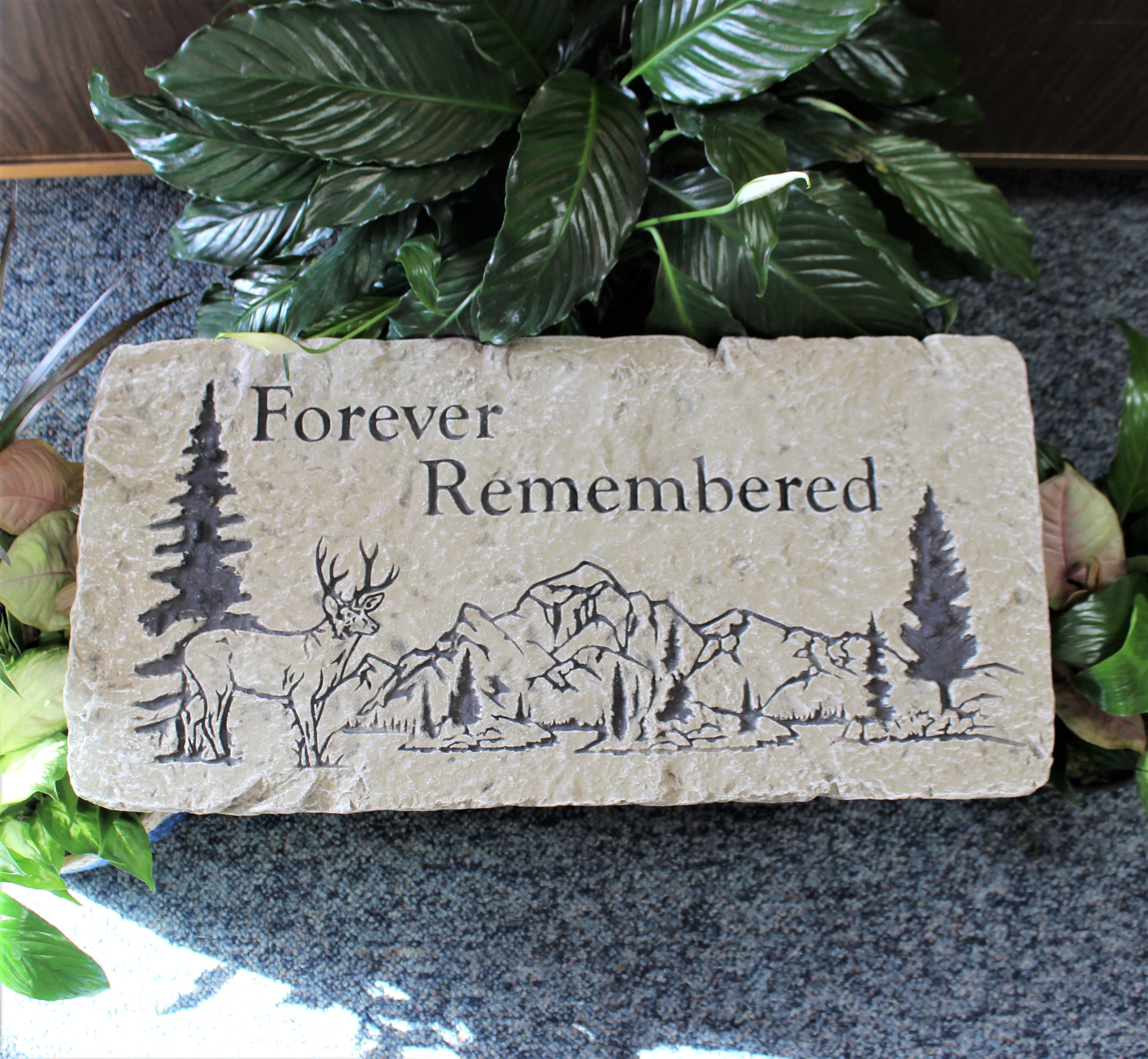 Stone memorial plaque engraved with a deer and mountains